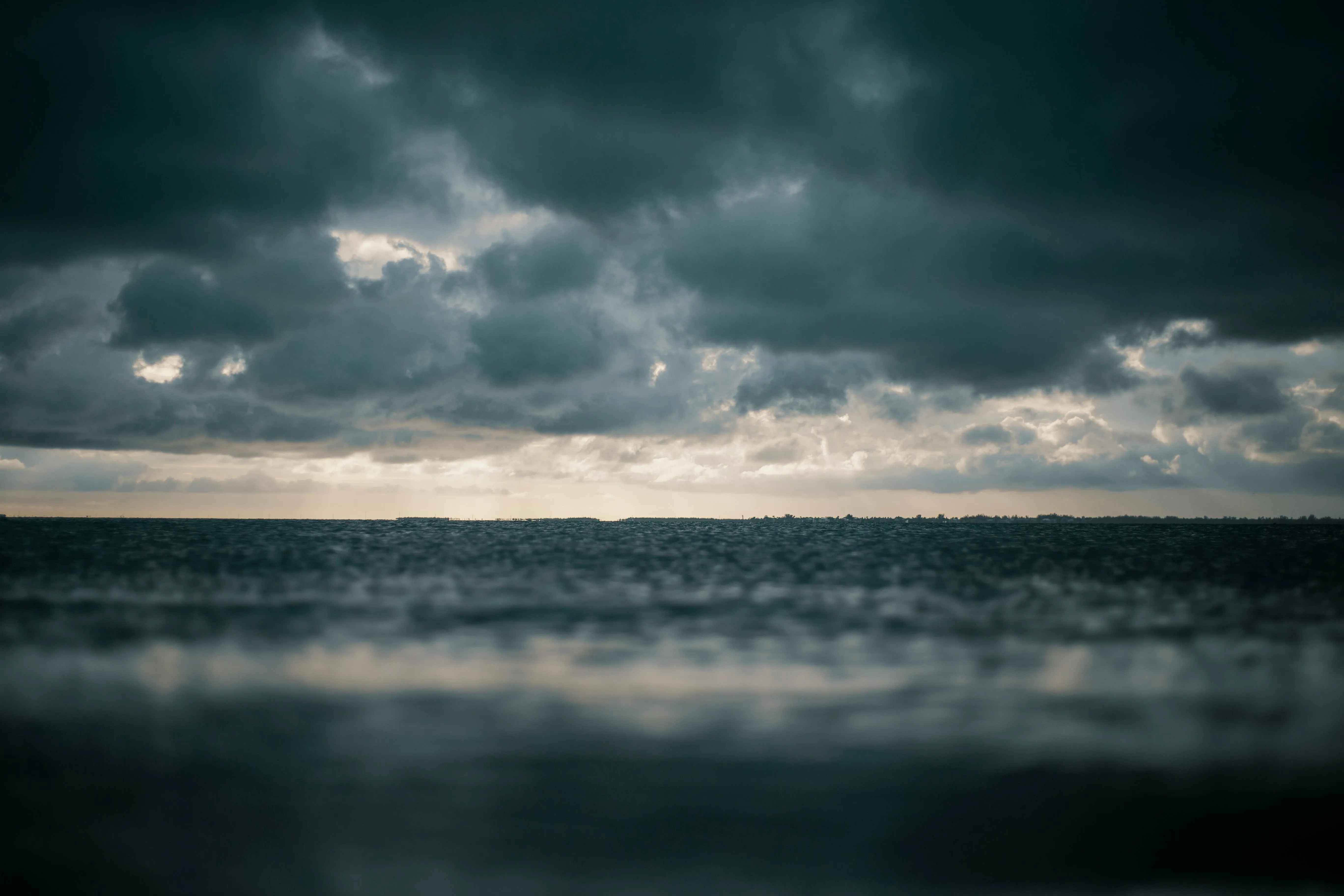 Moody Dark Clouds Reflecting on Calm Ocean Surface Image