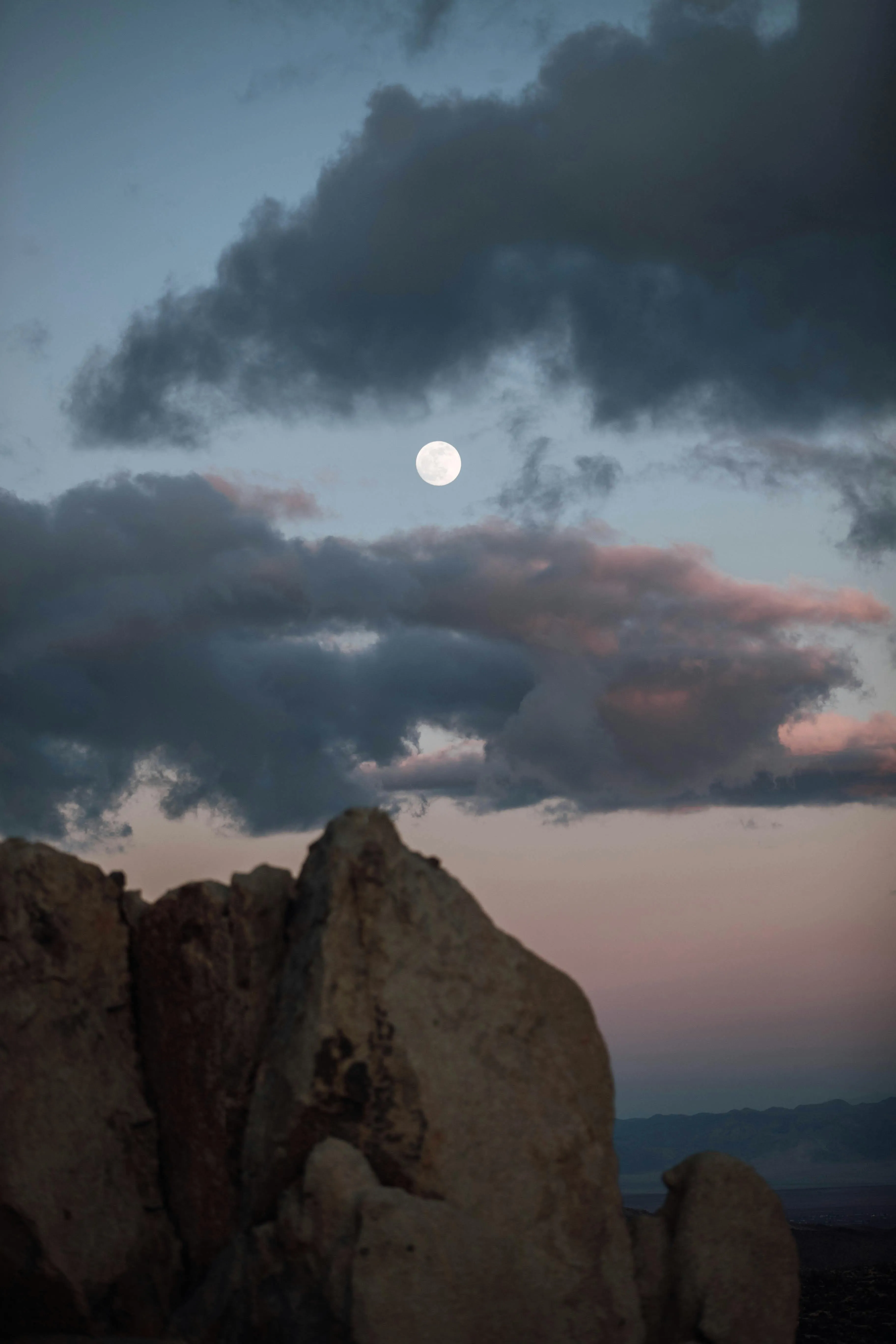 Moon Shining Bright in a Cloudy Sky Over Rocky Landscape