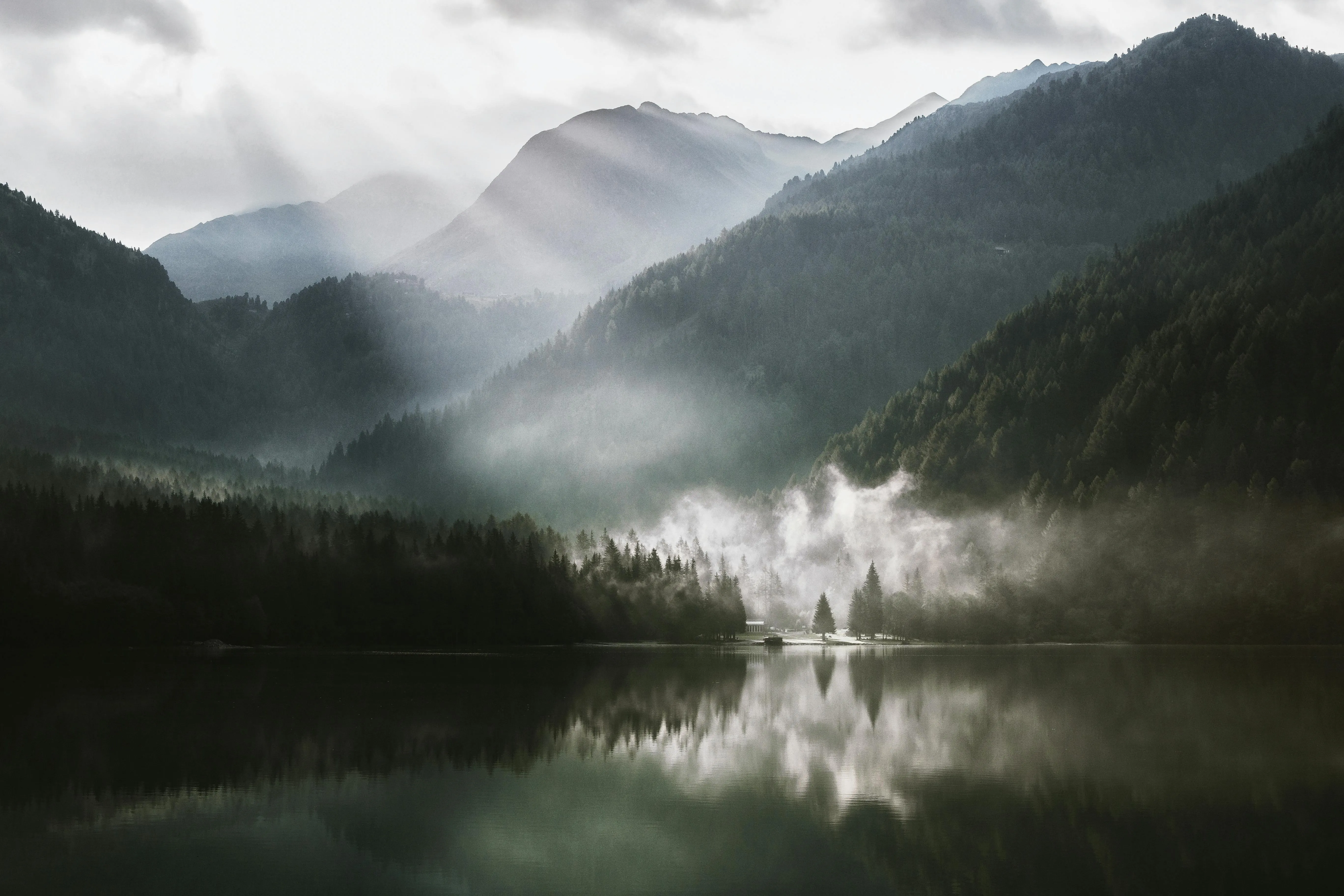 Morning Mist Over a Calm Lake Surrounded by Forested Hills