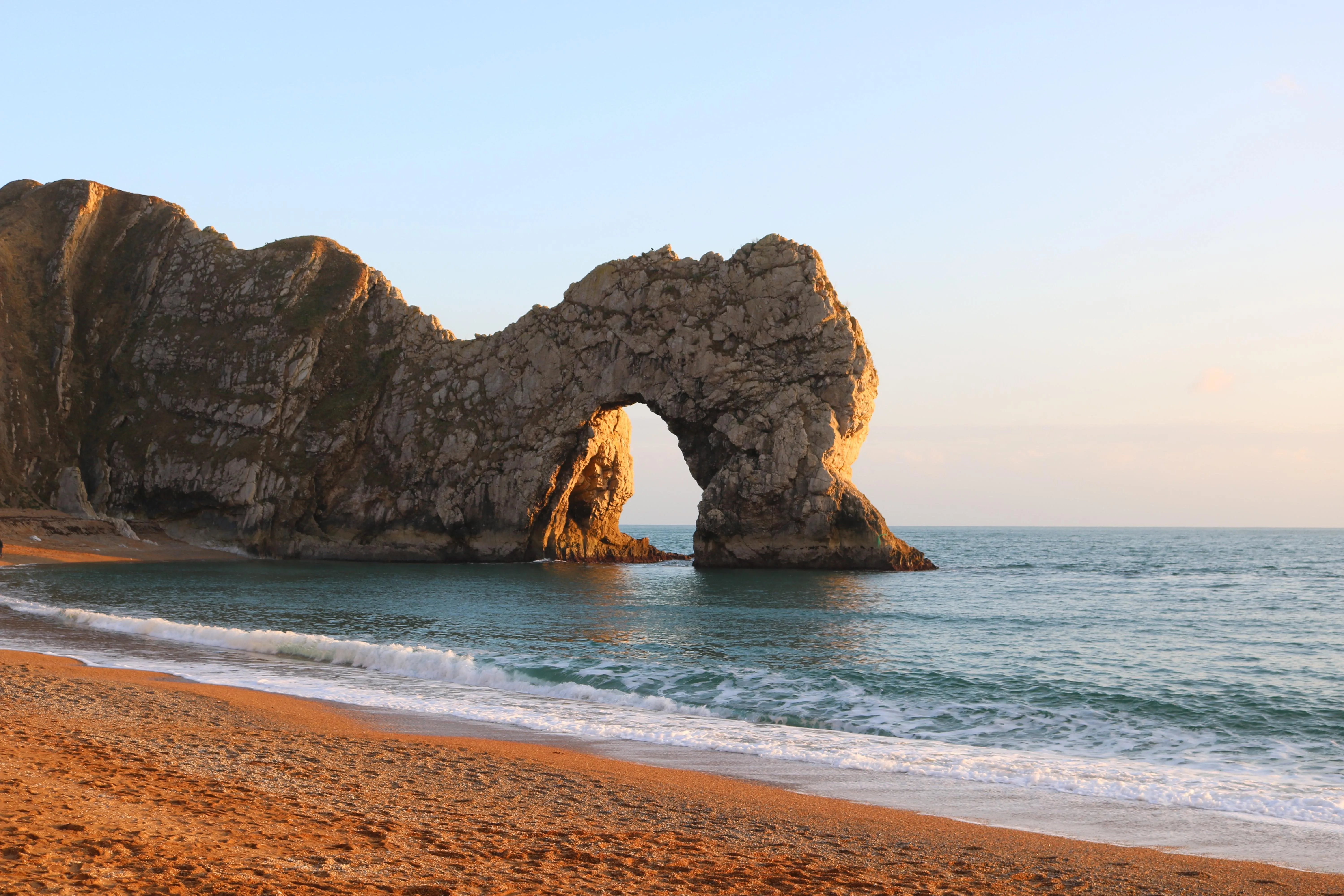 Natural Rock Arch by Calm Ocean Under Blue Sky image