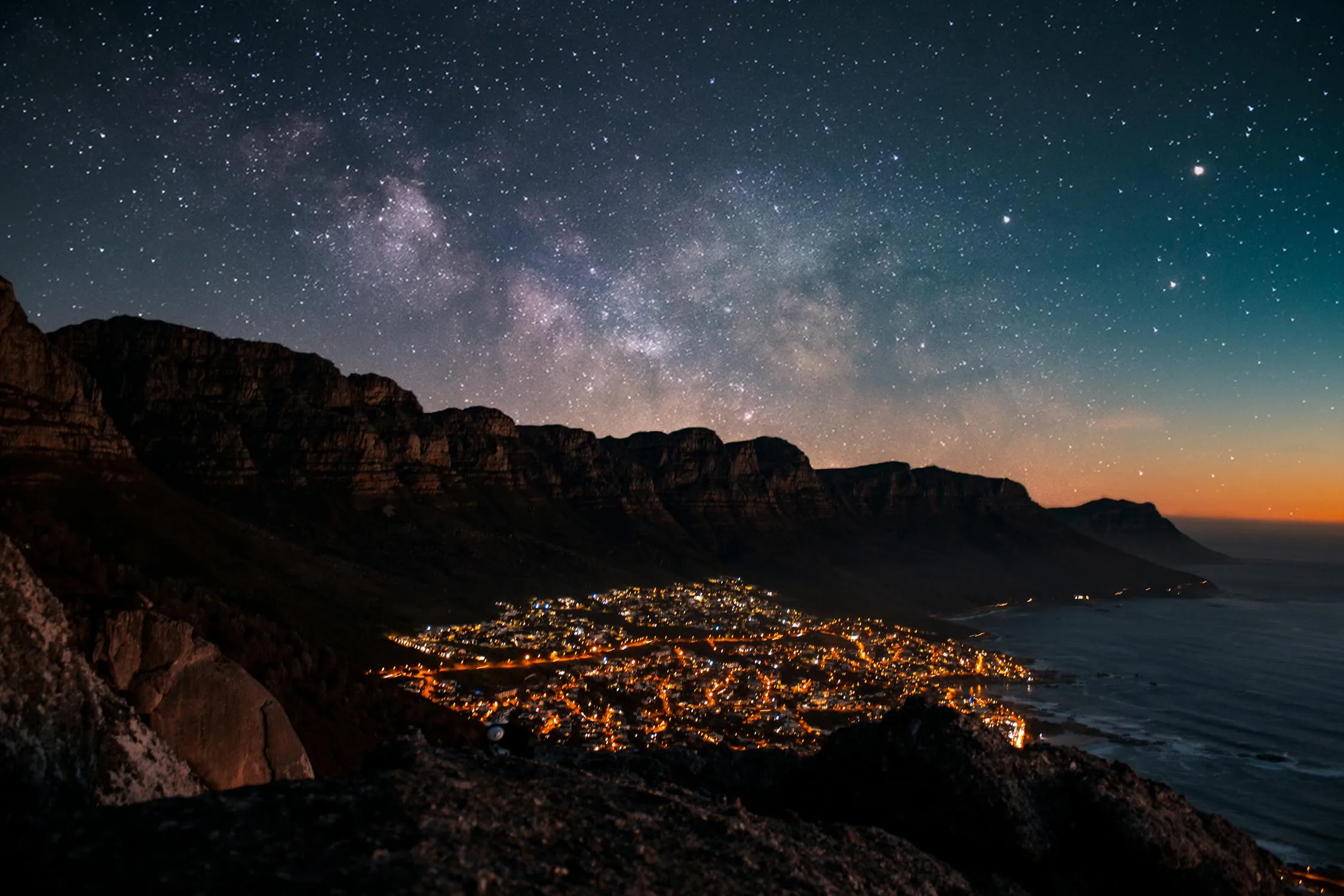 Night Coastal Town Under a Starry Sky and Clouds Image