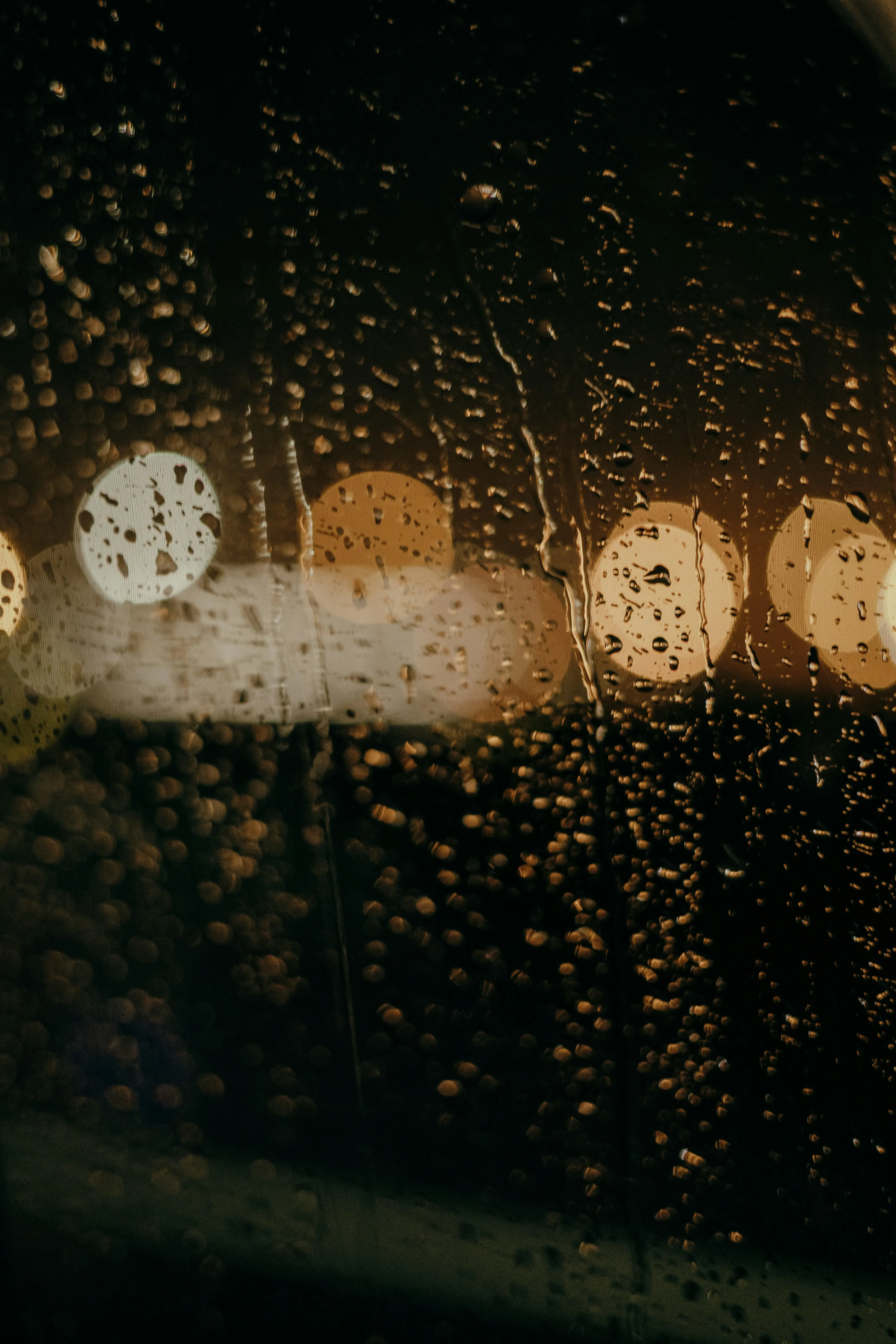 Night Rain Captured Through Blurred Glass with Warm Lights