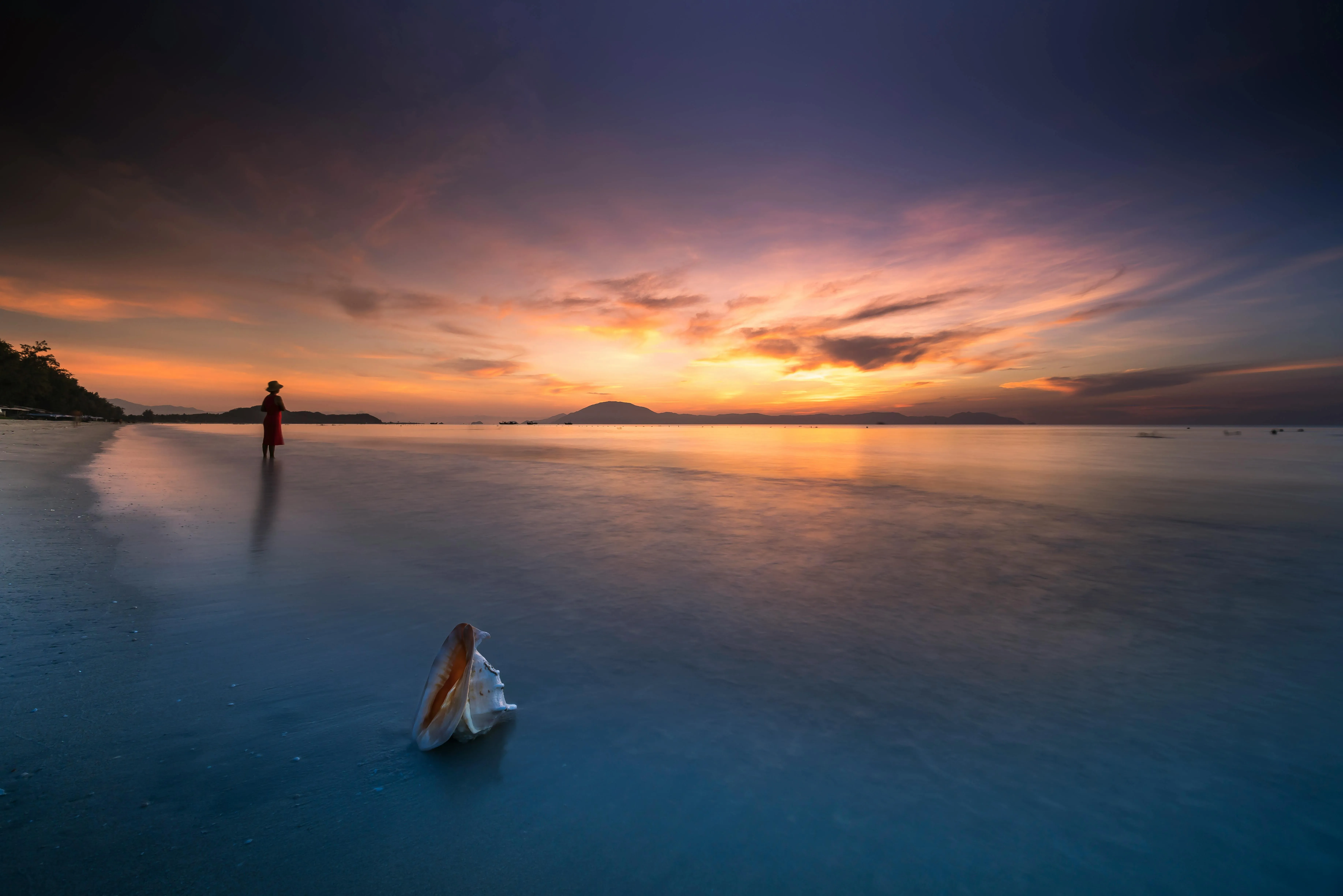 Ocean View with Women Under Golden Sunset and Calm Clouds