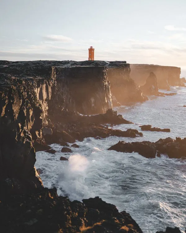 Ocean Waves Crashing Against Cliffs Under Cloudy Sky