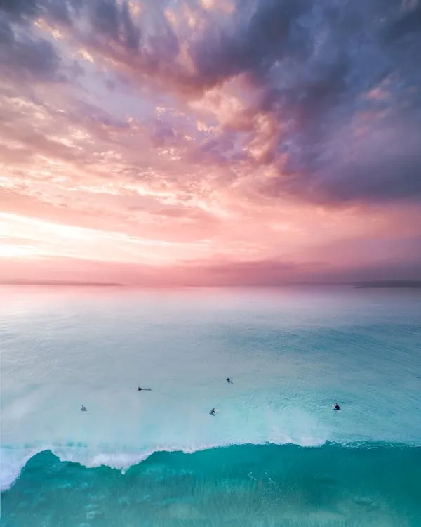 Ocean Waves Under Soft Pink Sunset and Cloud Cover Image