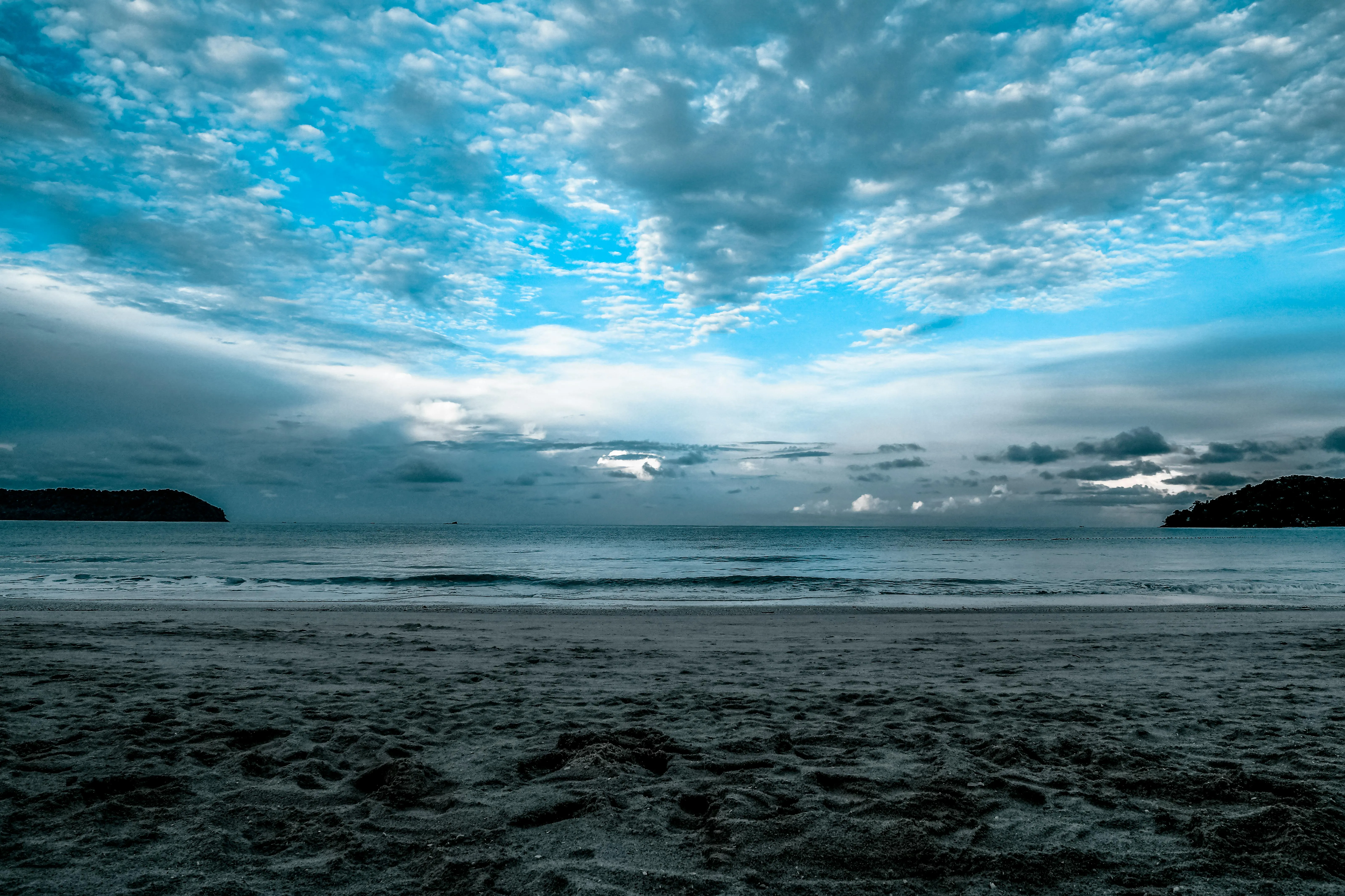 Ocean Waves Under Wide Blue Sky with Cloud Layers Image