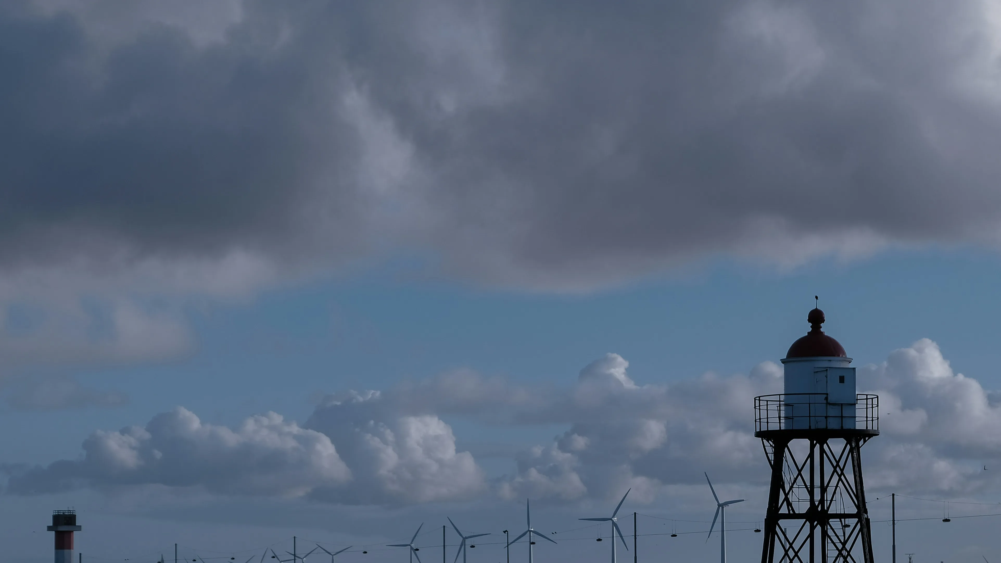 Old Lighthouse Standing Tall Under Cloudy Skywallpaper