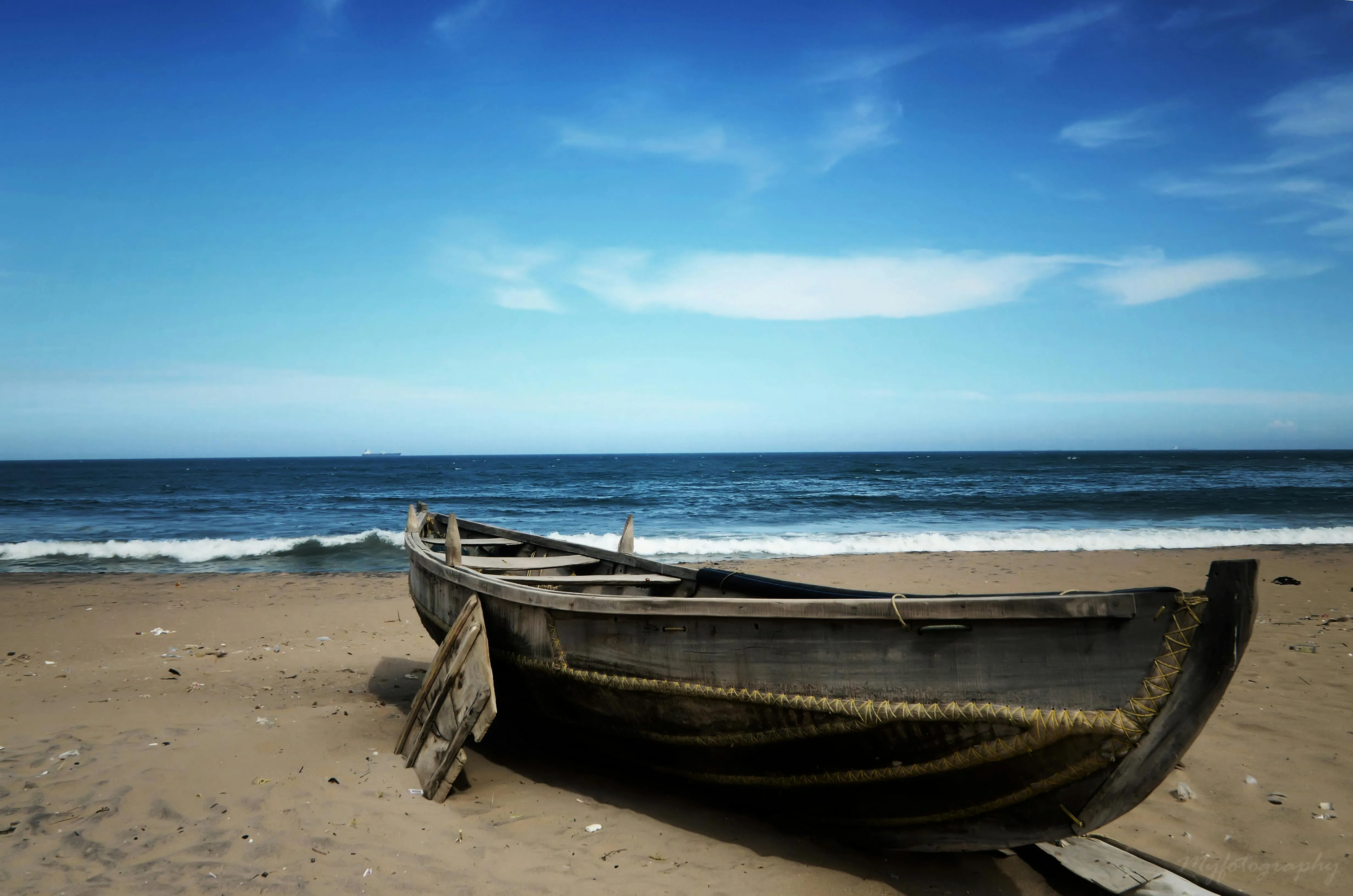 Old Wooden Boat Resting on a Sandy Beach Under Blue Sky