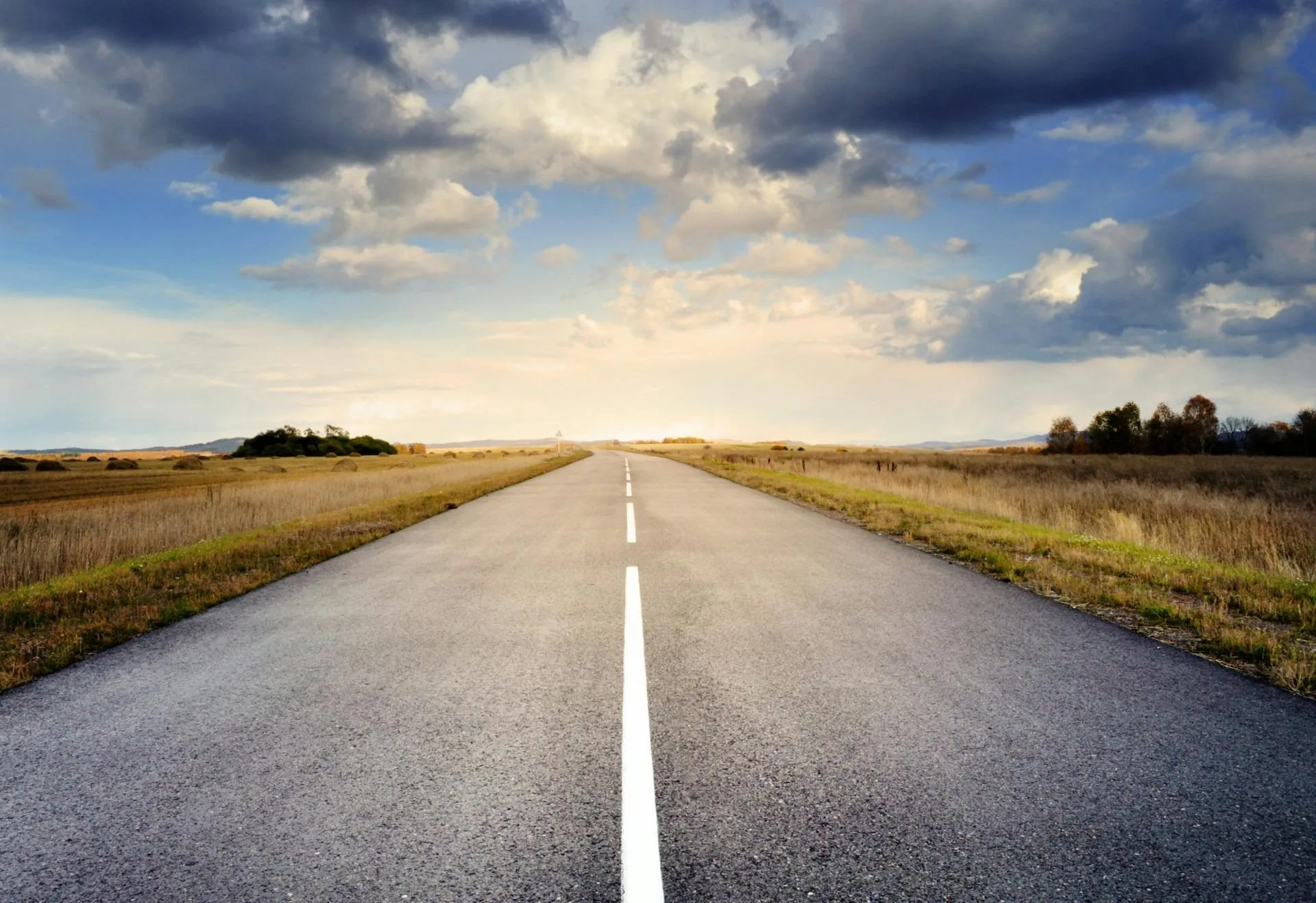 Open Road Leading To Horizon with Blue Sky and Clouds Above