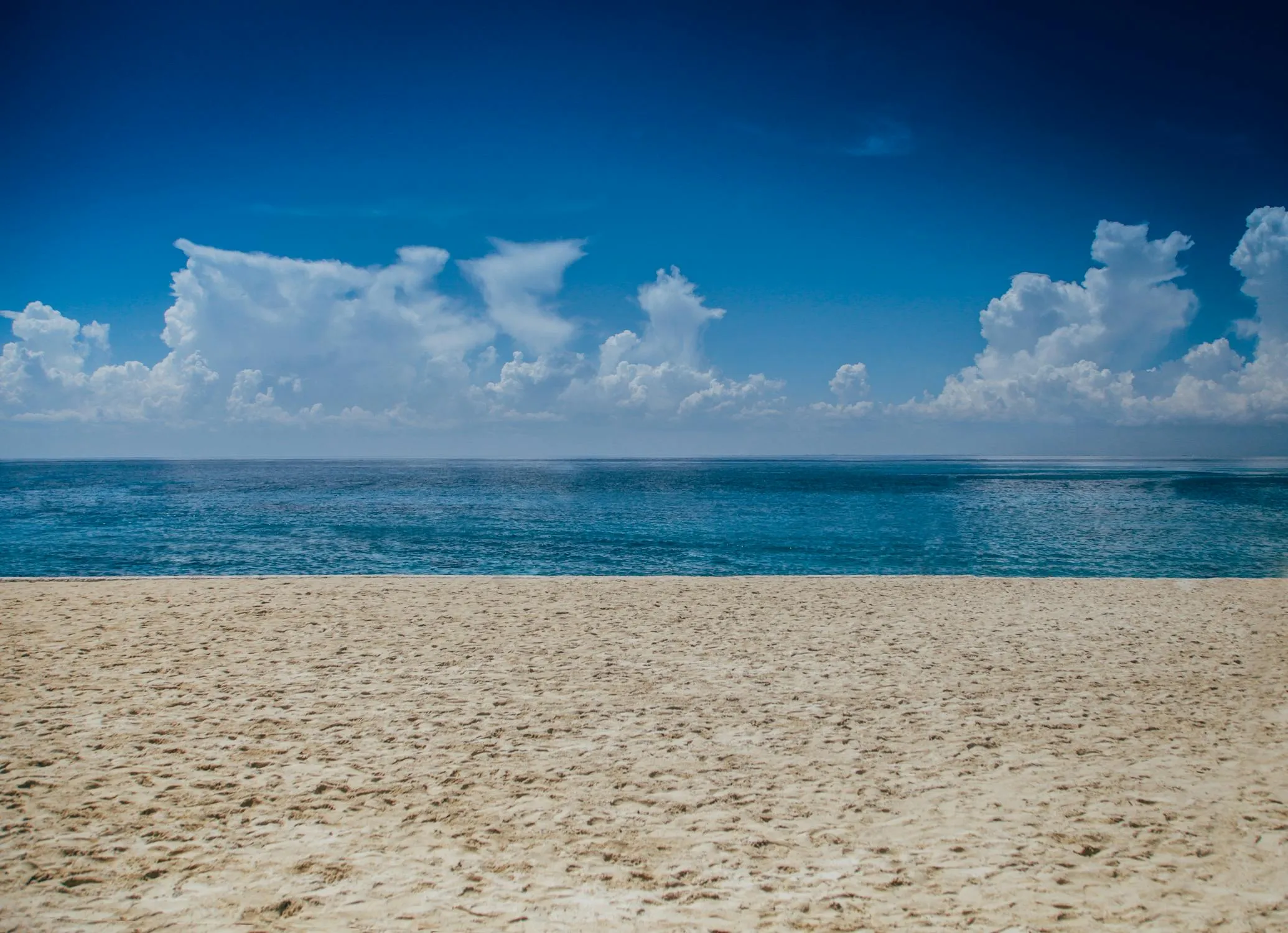 Peaceful Beach with Blue Ocean and Clear Sky Wallpaper