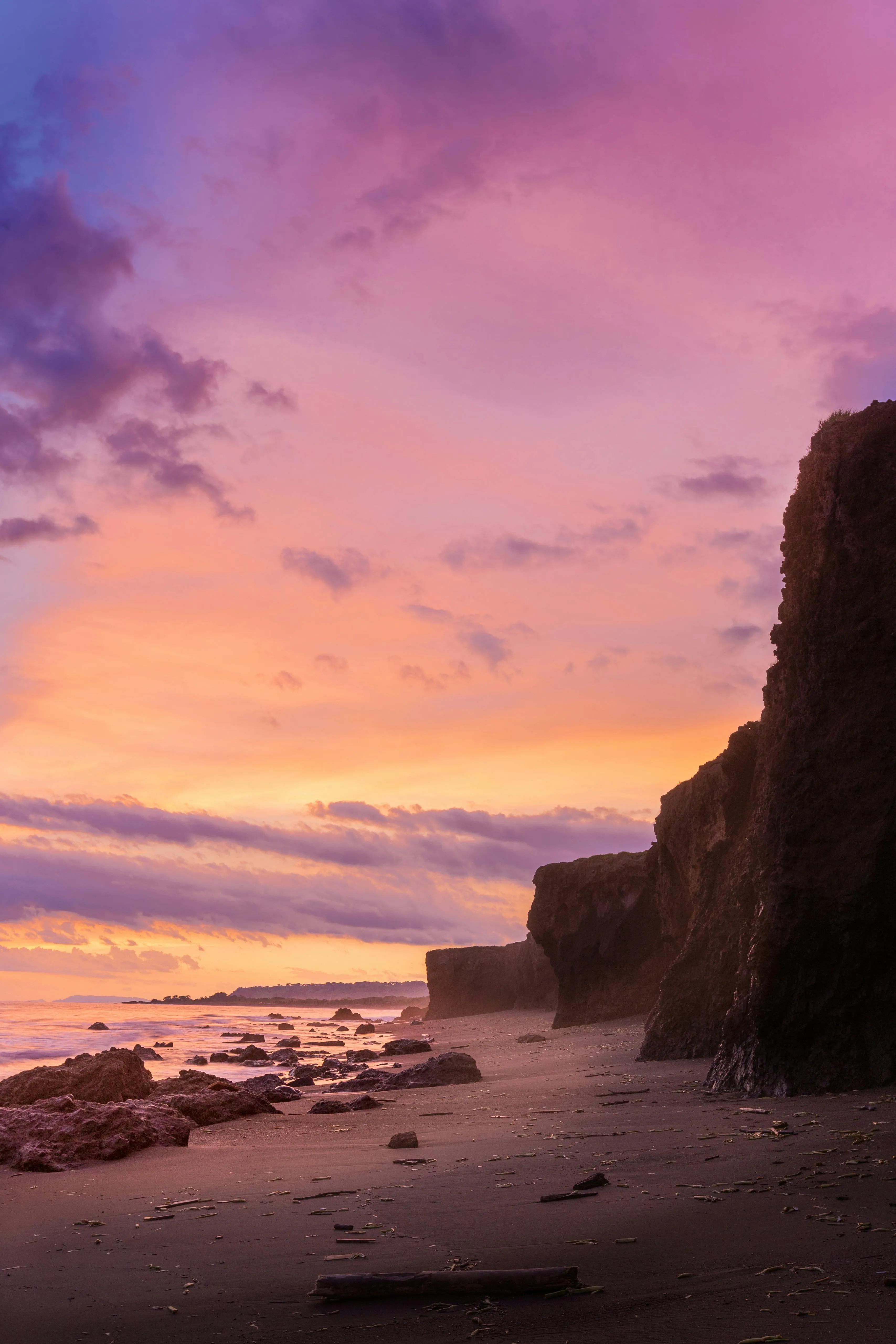Peaceful Beach with Pink Sky and Rocky Cliffs Wallpaper