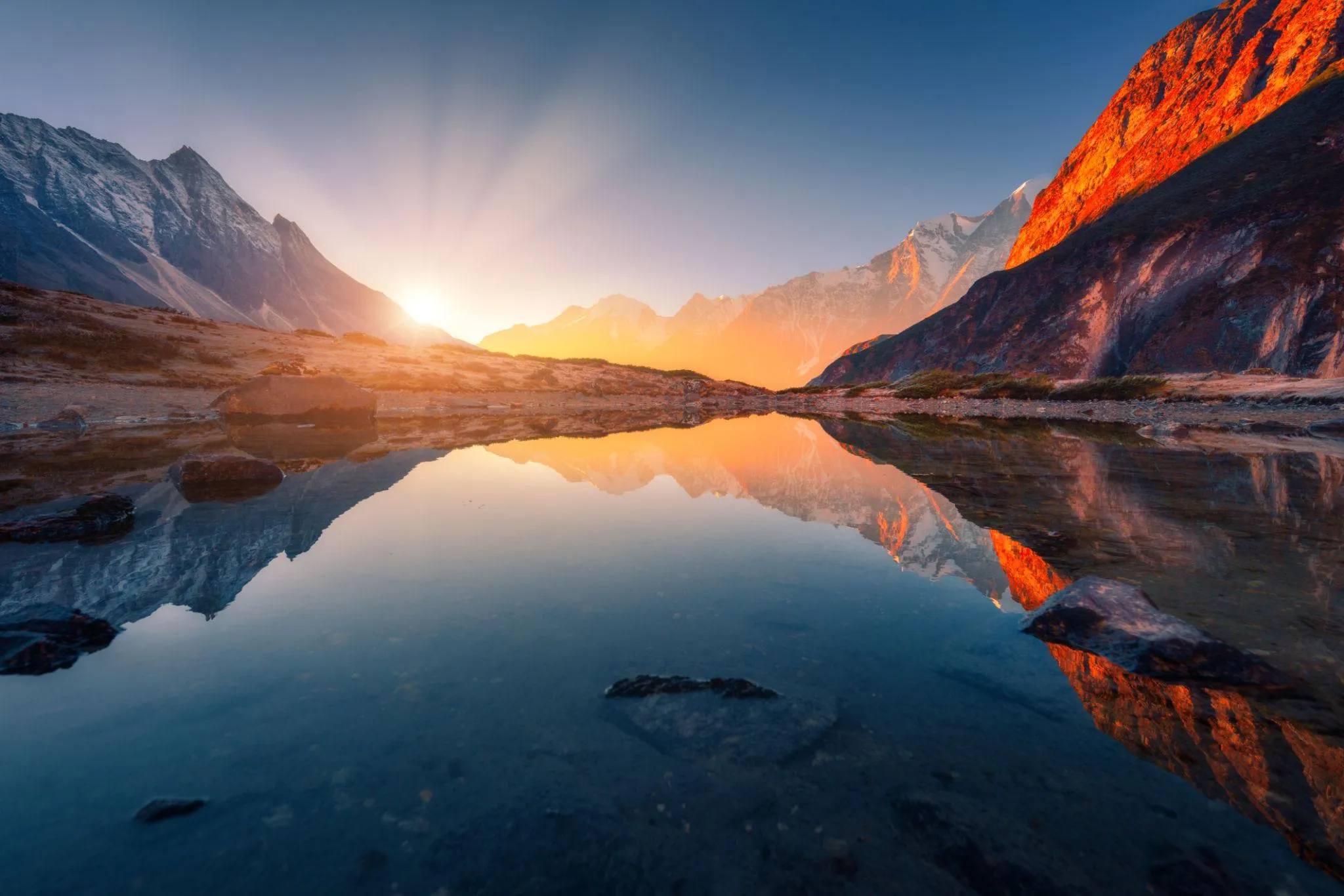 Peaceful lake surrounded by snowy mountains at dusk