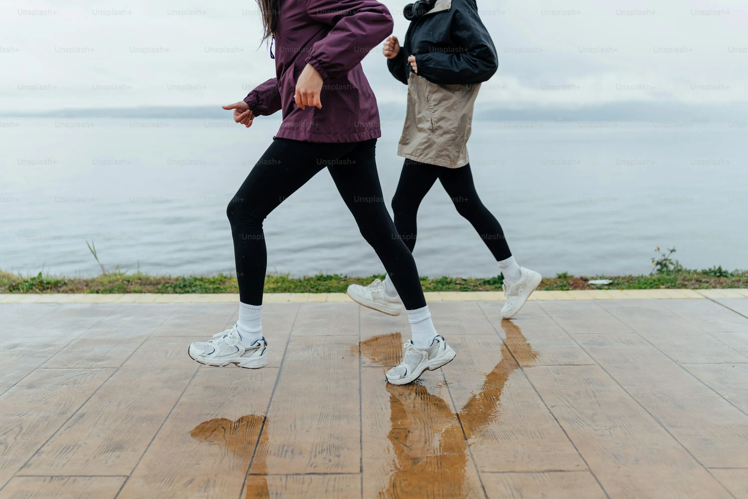 People Running Along Beach Wearing Rain Clothes
