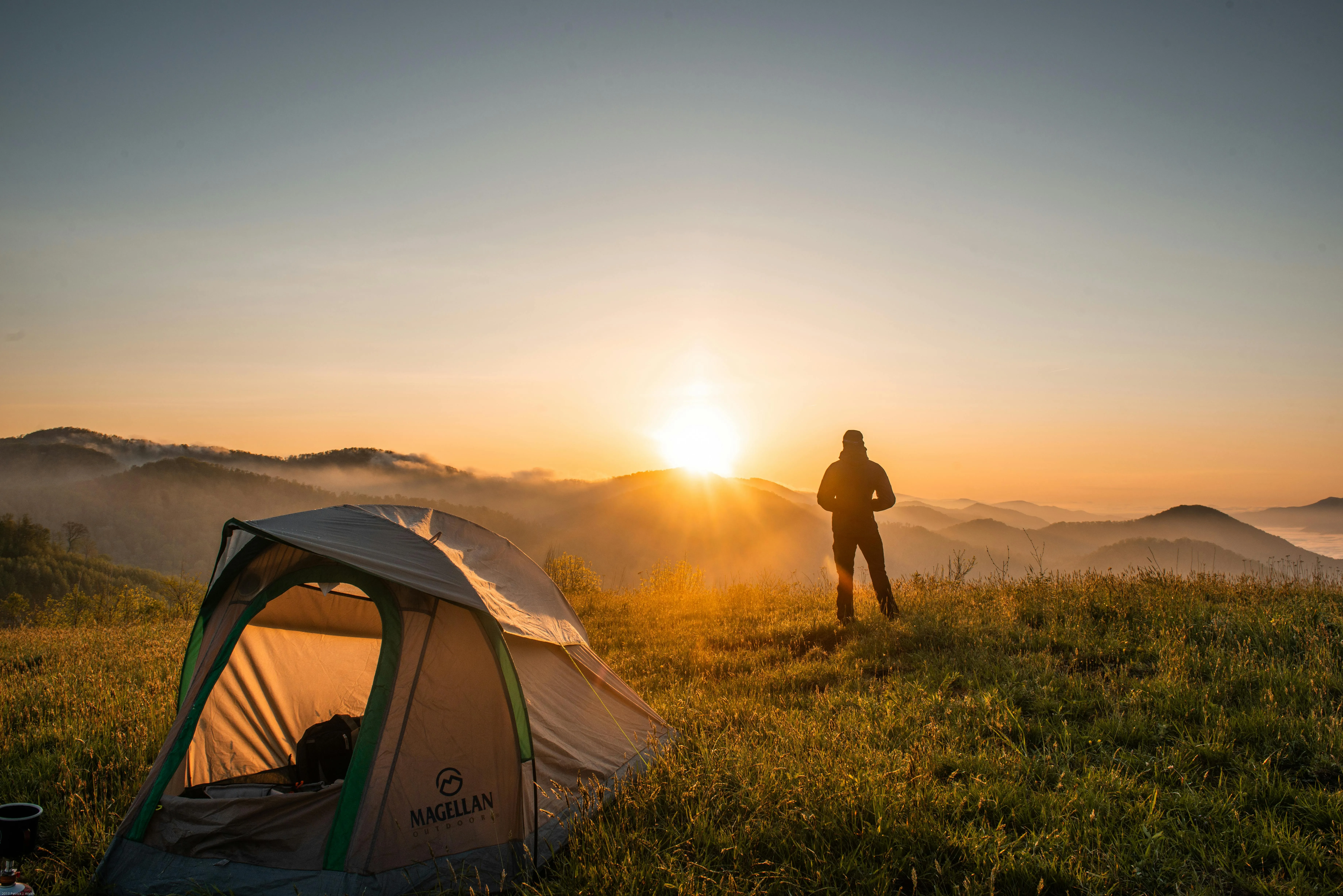 Person Camping in Field During Stunning Sunset Sky Photo