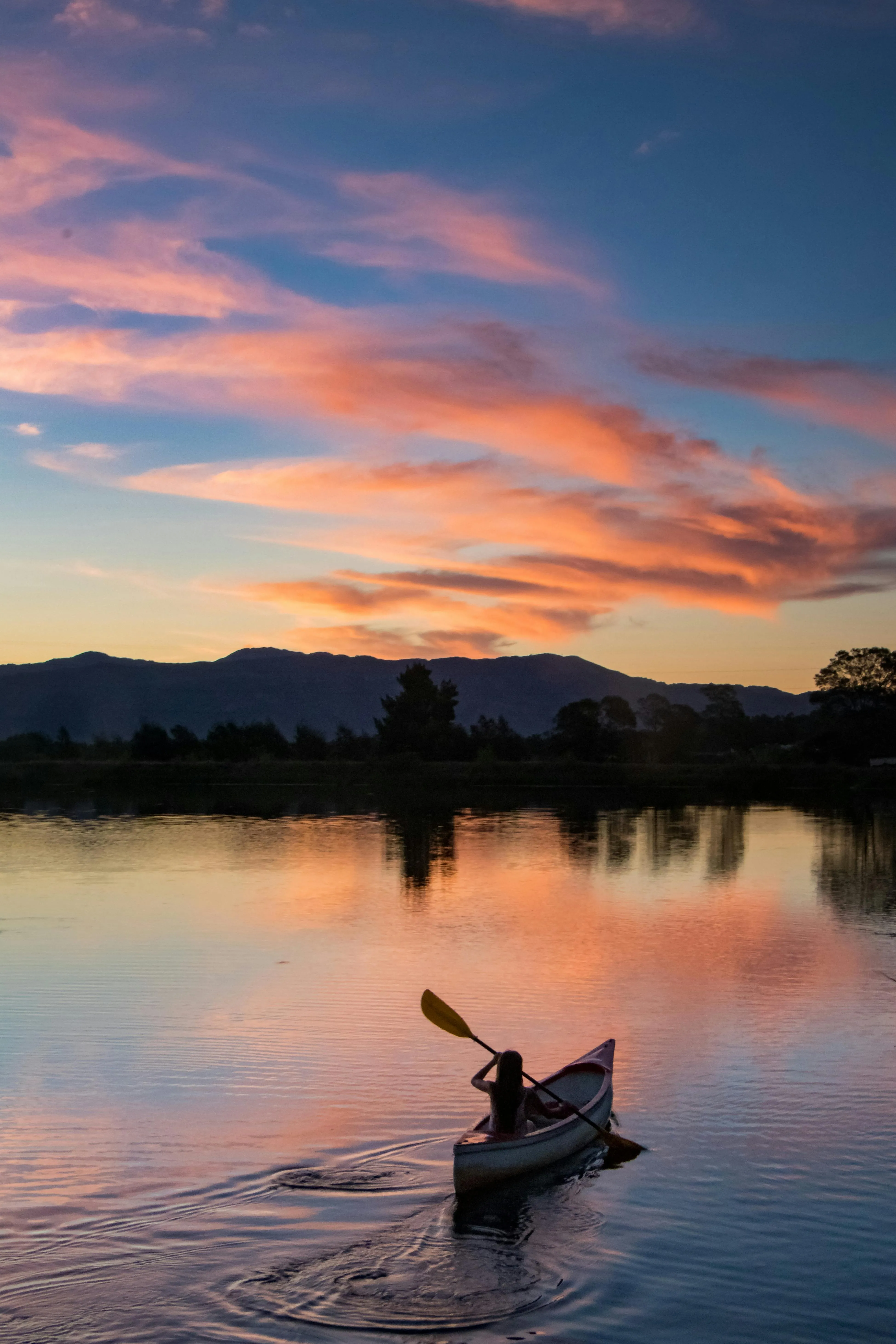 Person in Kayak During Sunset with Vivid Cloud Reflections