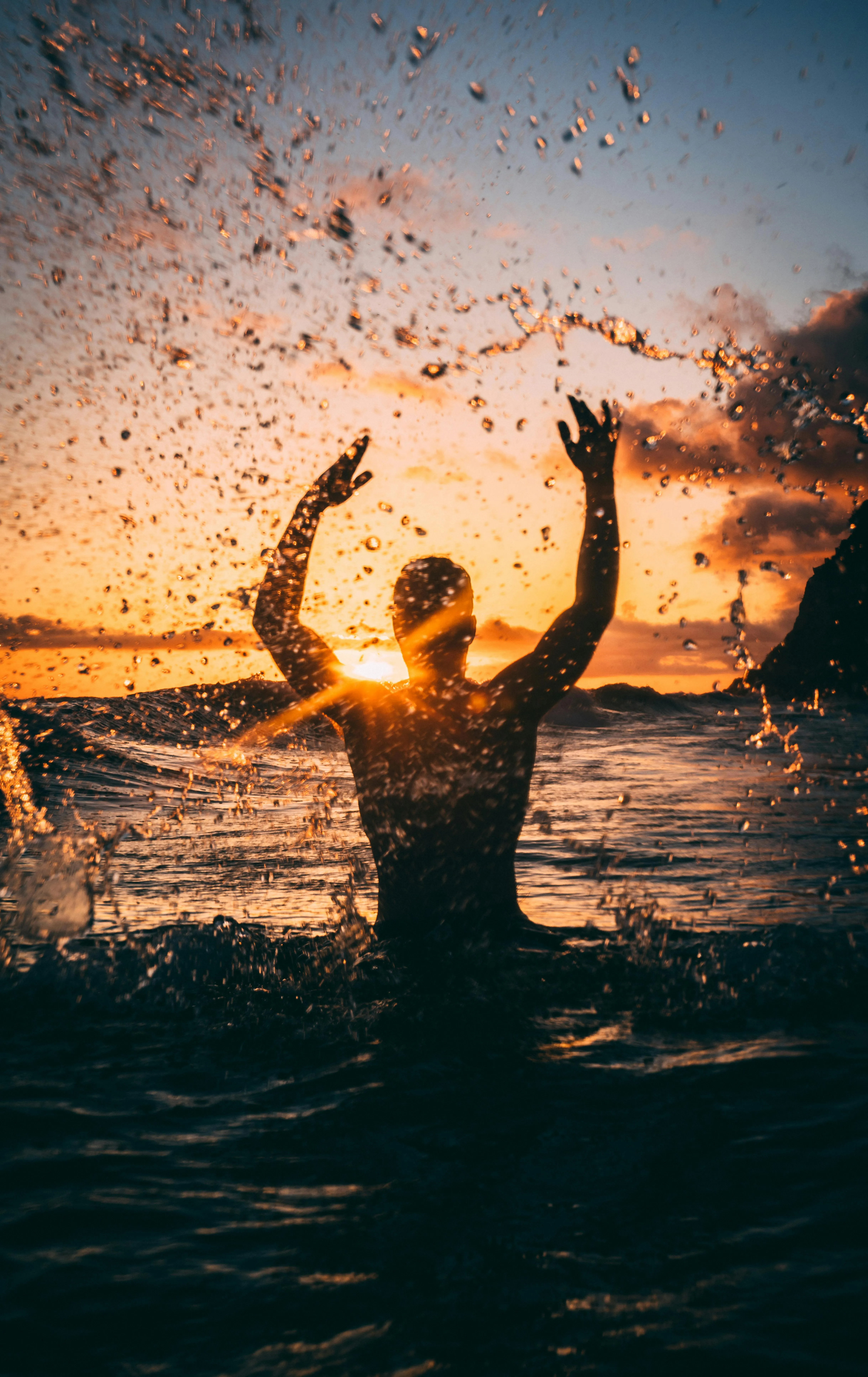 Person Jumping in Water Creating Splash Under Sunset Sky