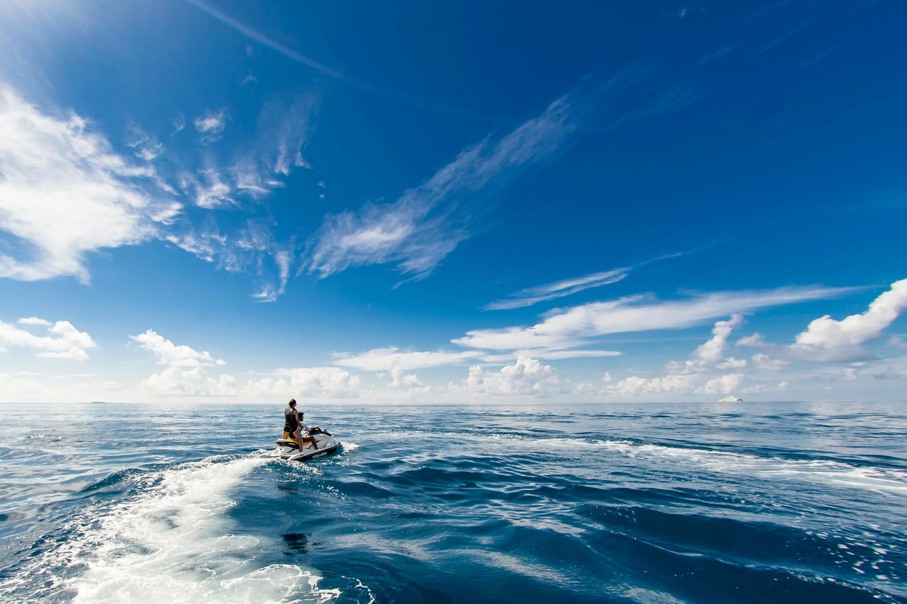 Person Paddling Boat in Ocean with Clear Blue Sky Wallpaper