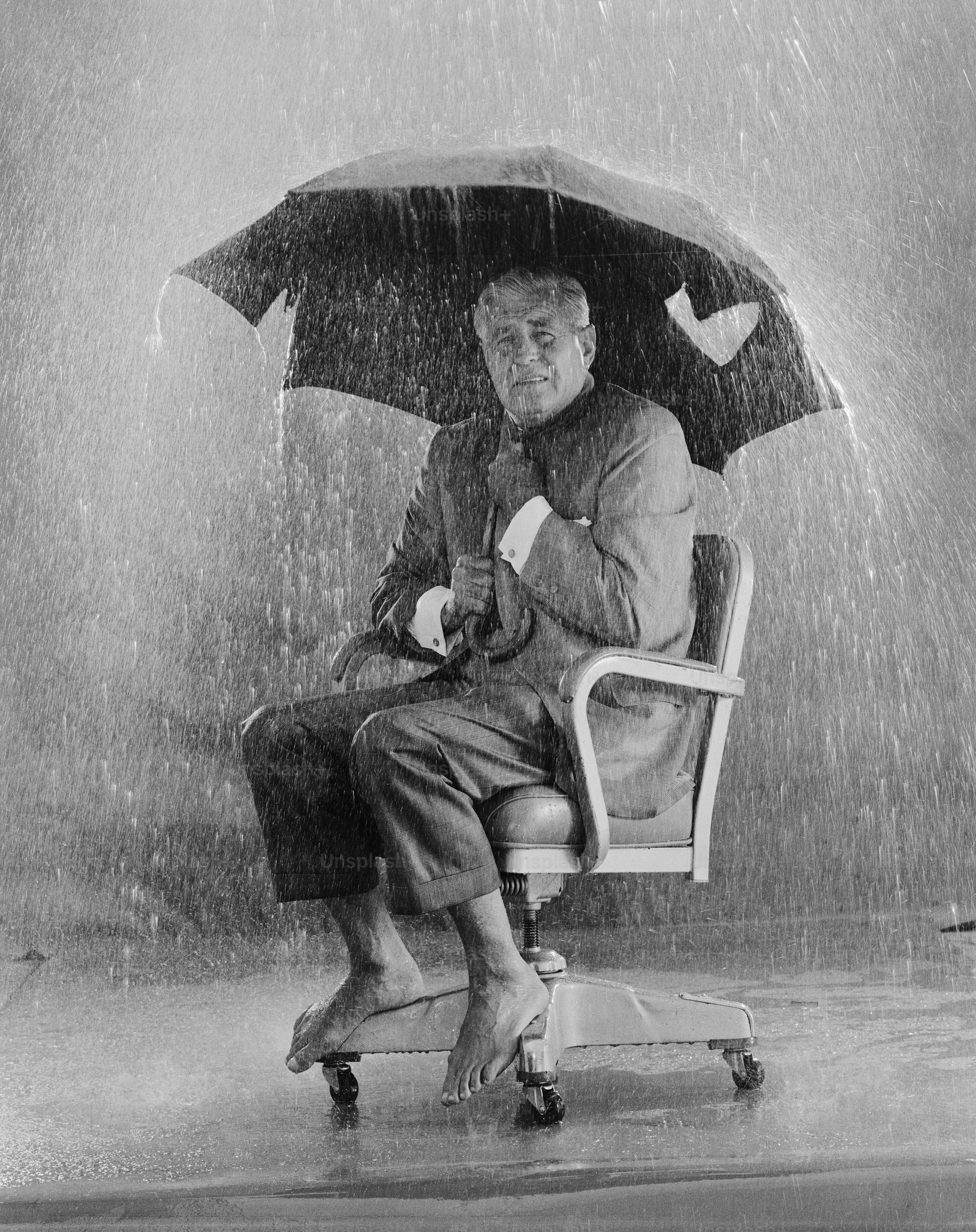 Person Sitting with Umbrella During Heavy Downpour