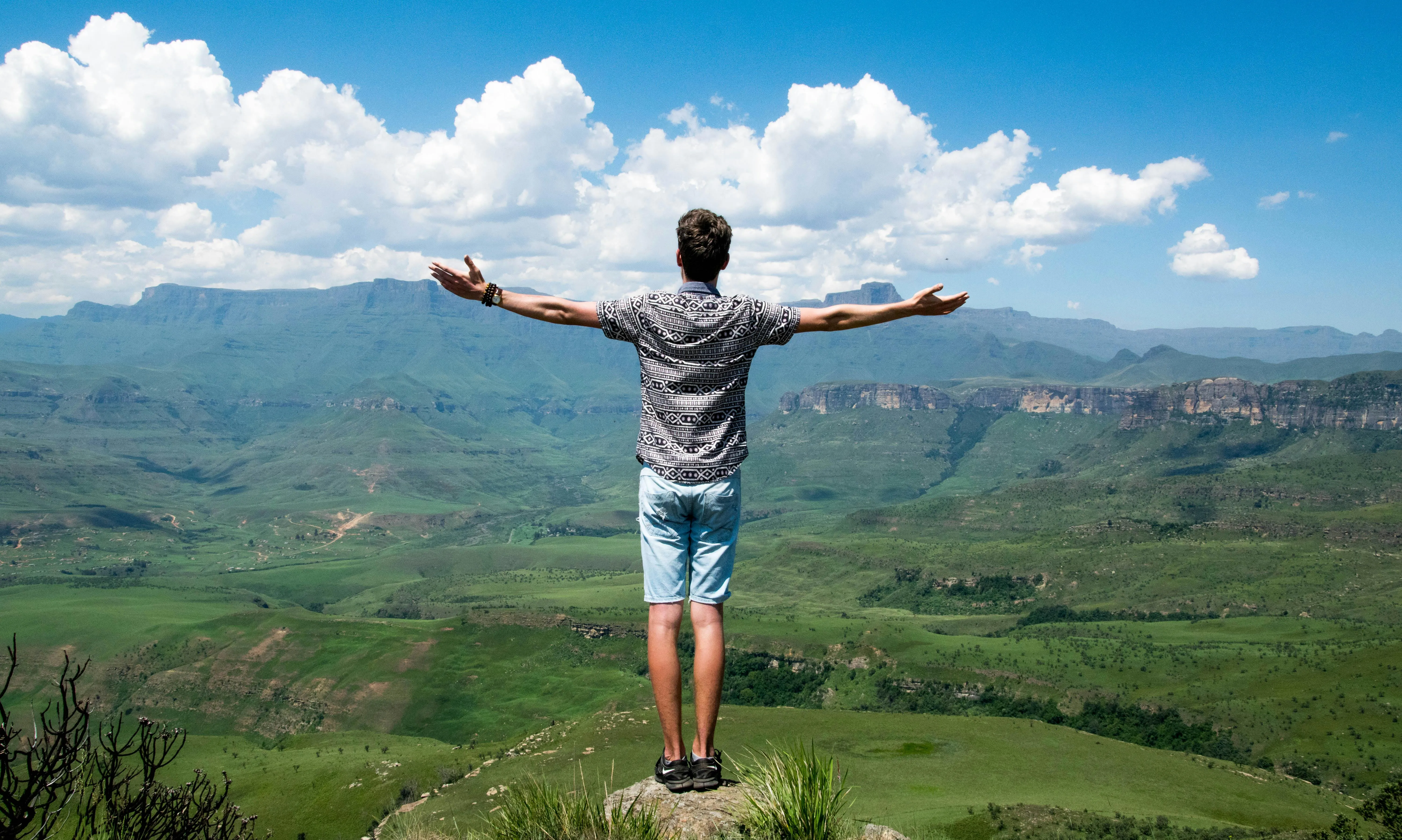 Person Standing with Arms Raised Enjoying Scenic Mountain View