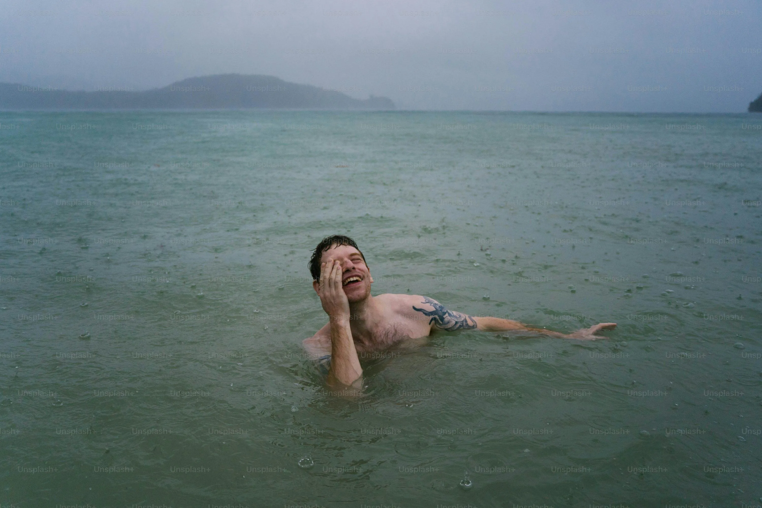 Person Swimming in Calm Sea with Cloudy Sky and Rain Drops
