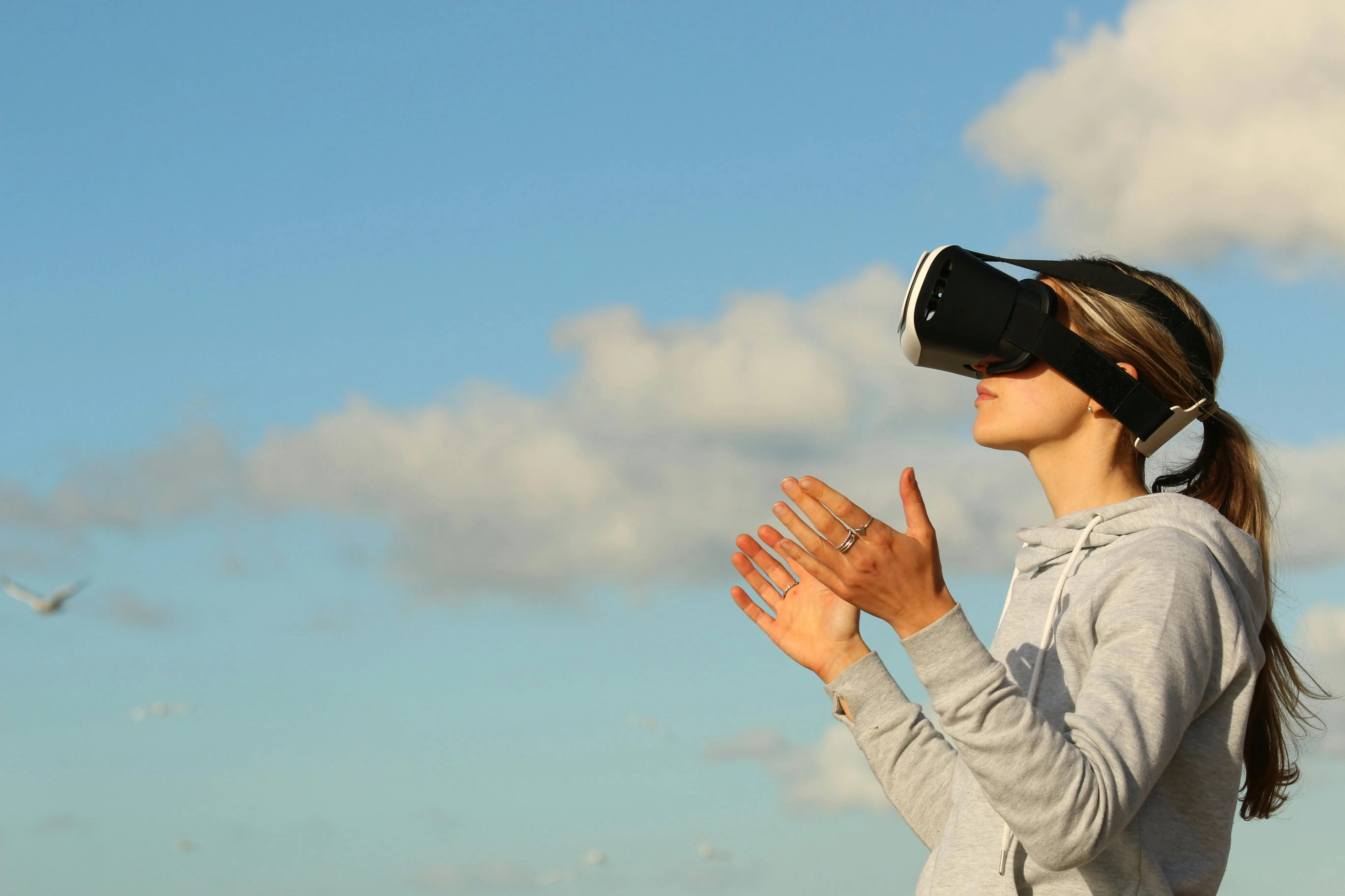 Person Using Virtual Reality Headset Under Cloudy Sky
