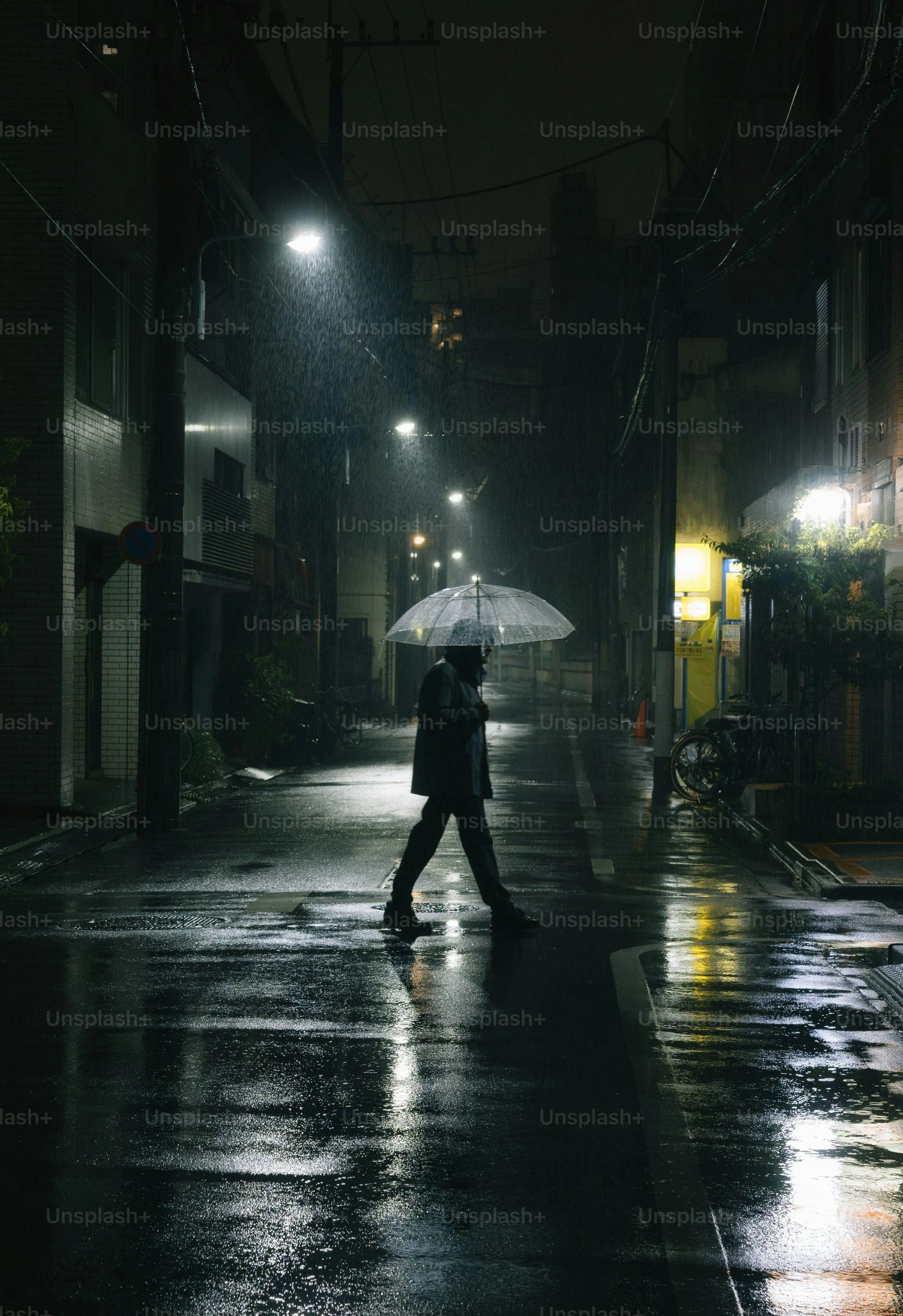 Person Walking Alone on Rainy City Street at Night
