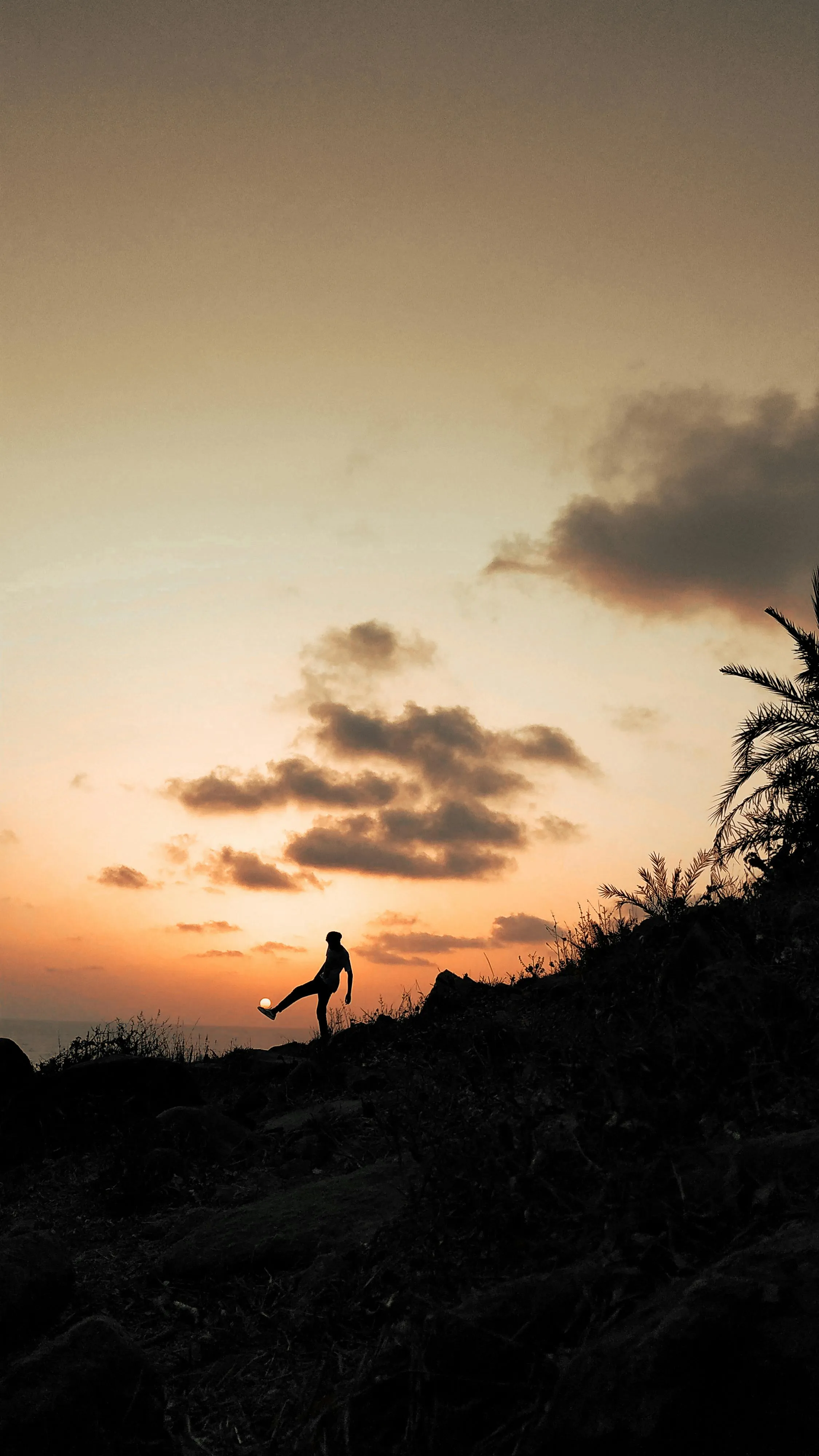 Person Walking at Dusk Beneath Glowing Orange Clouds