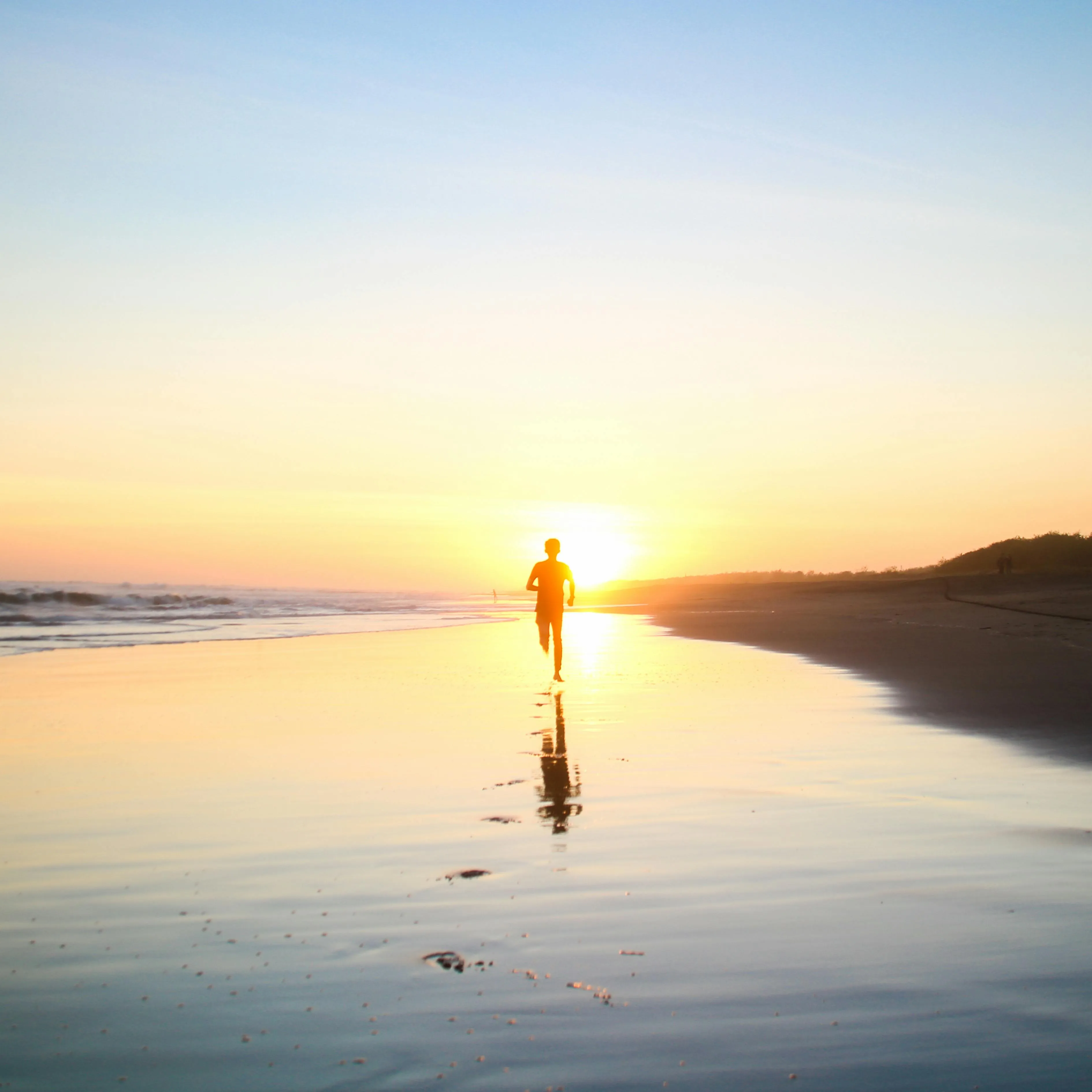 Person Walking on Beach with Reflection and Cloud Sky