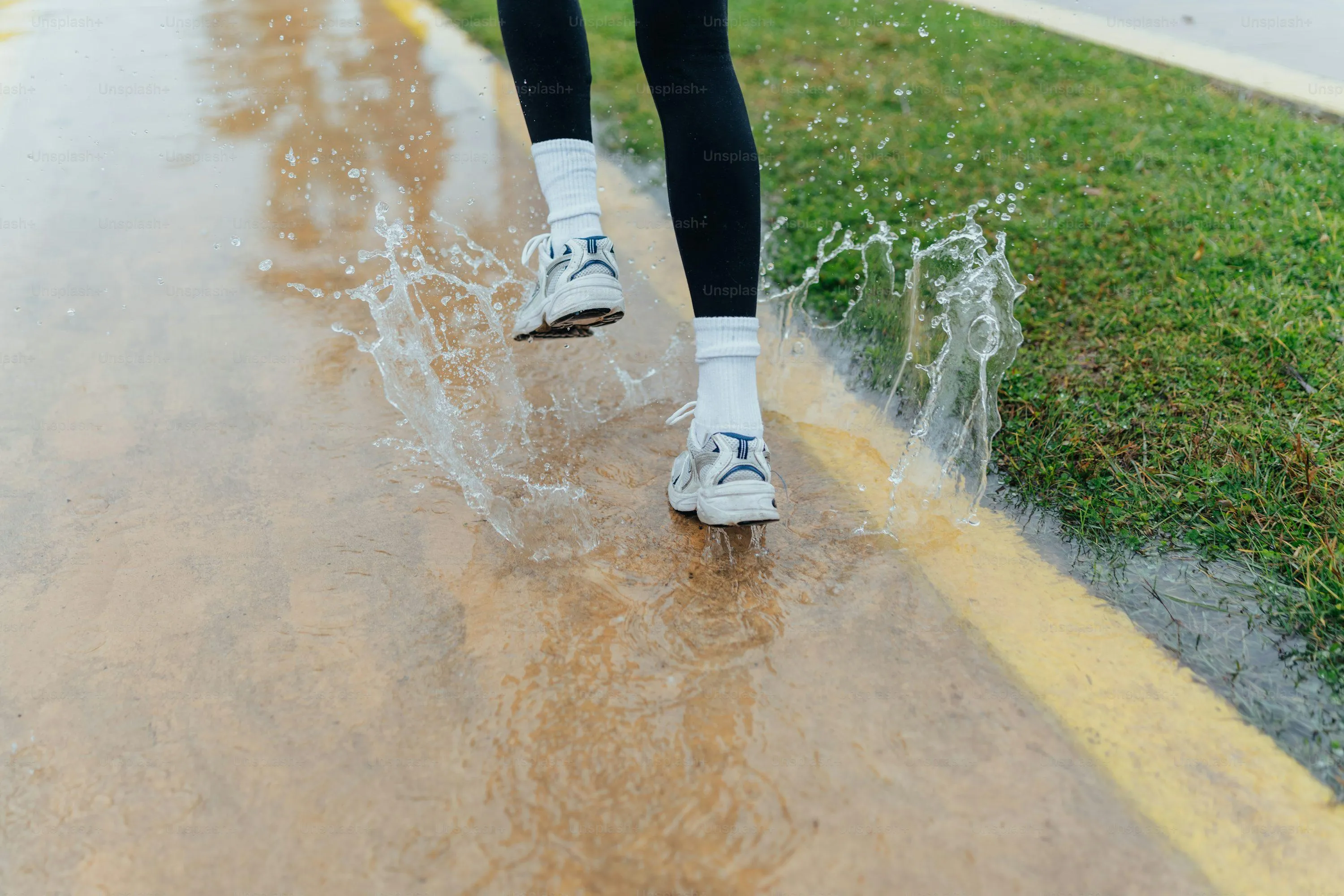 Person Walking on Wet Pavement on Rainy Day Wallpaper