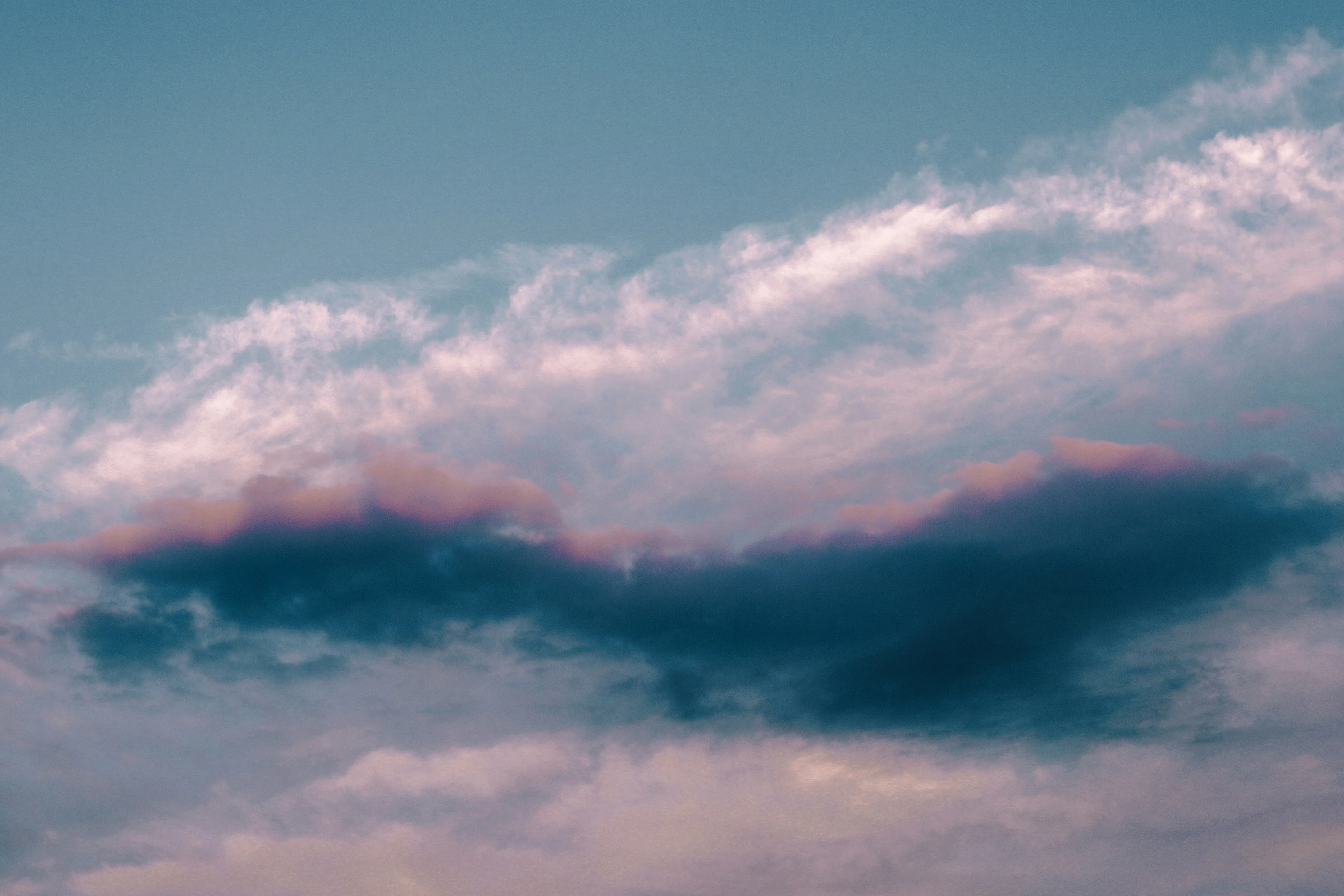 Pink Tinged Clouds Floating Gently in a Blue Sky Wallpaper