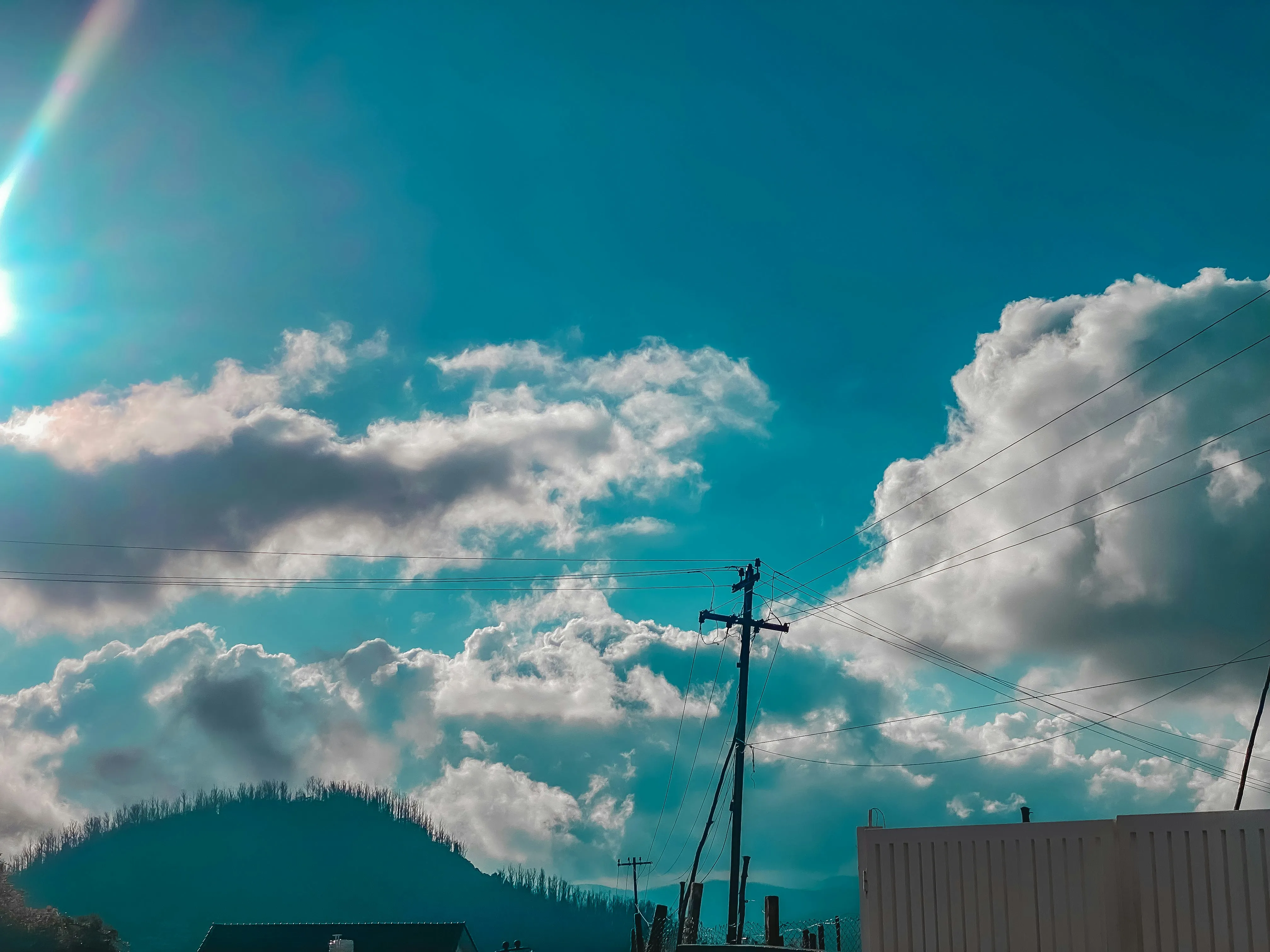 Power Lines Stretch Across Sky with Thick Clouds and Sunlight
