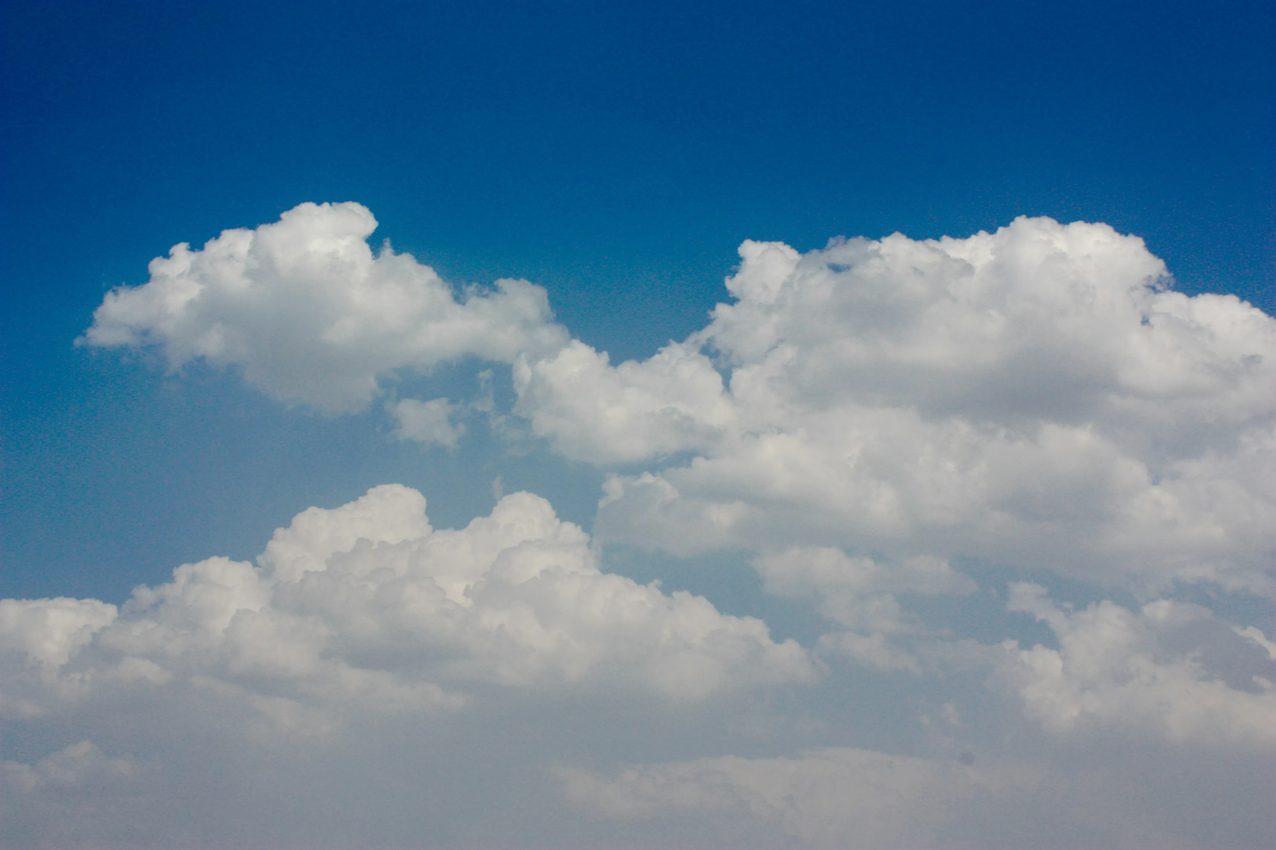 Puffy White Clouds in Deep Blue Sky Above Horizon Wallpaper