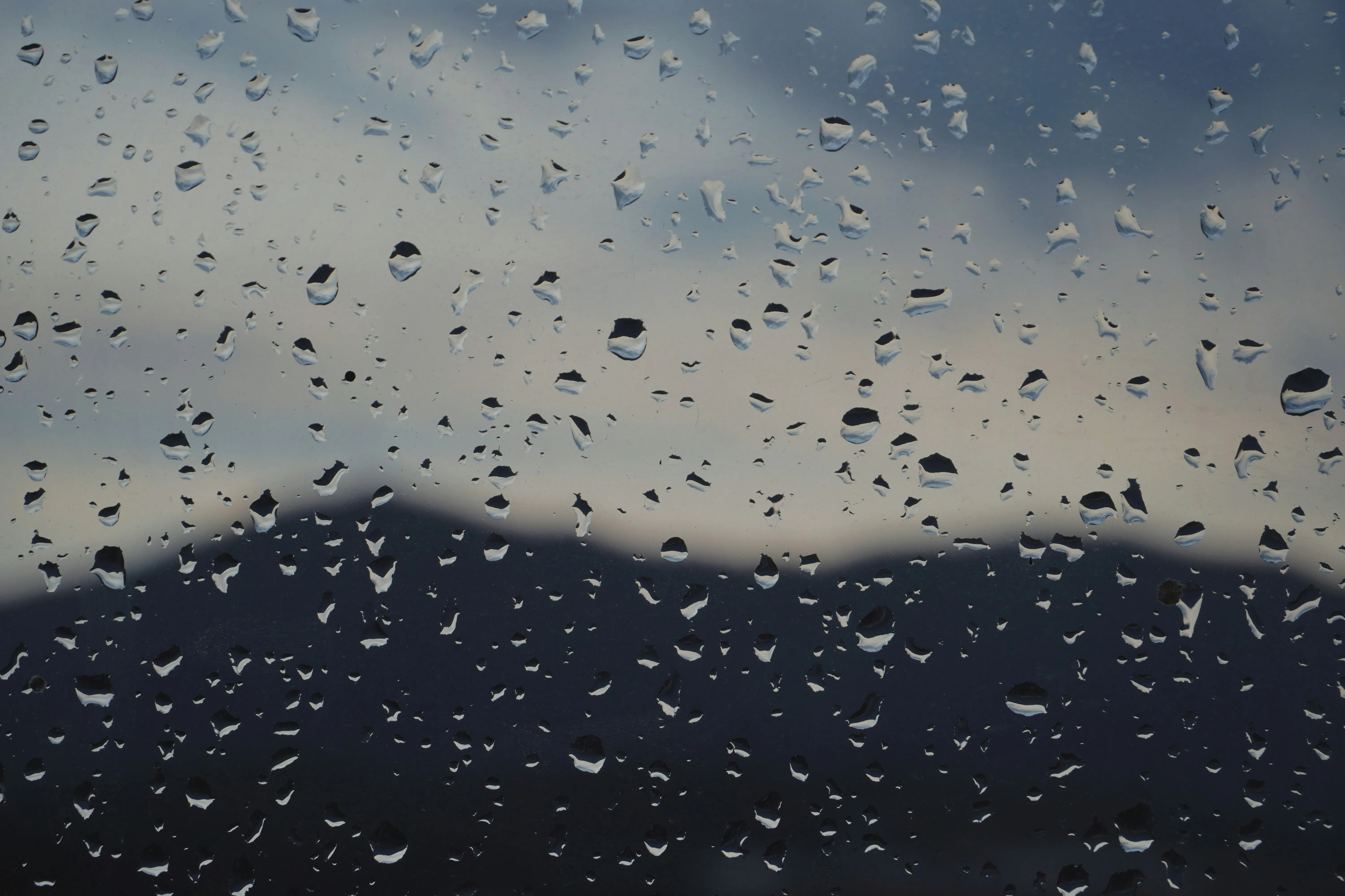 Rain Droplets on Window with Mountain View in the Distance