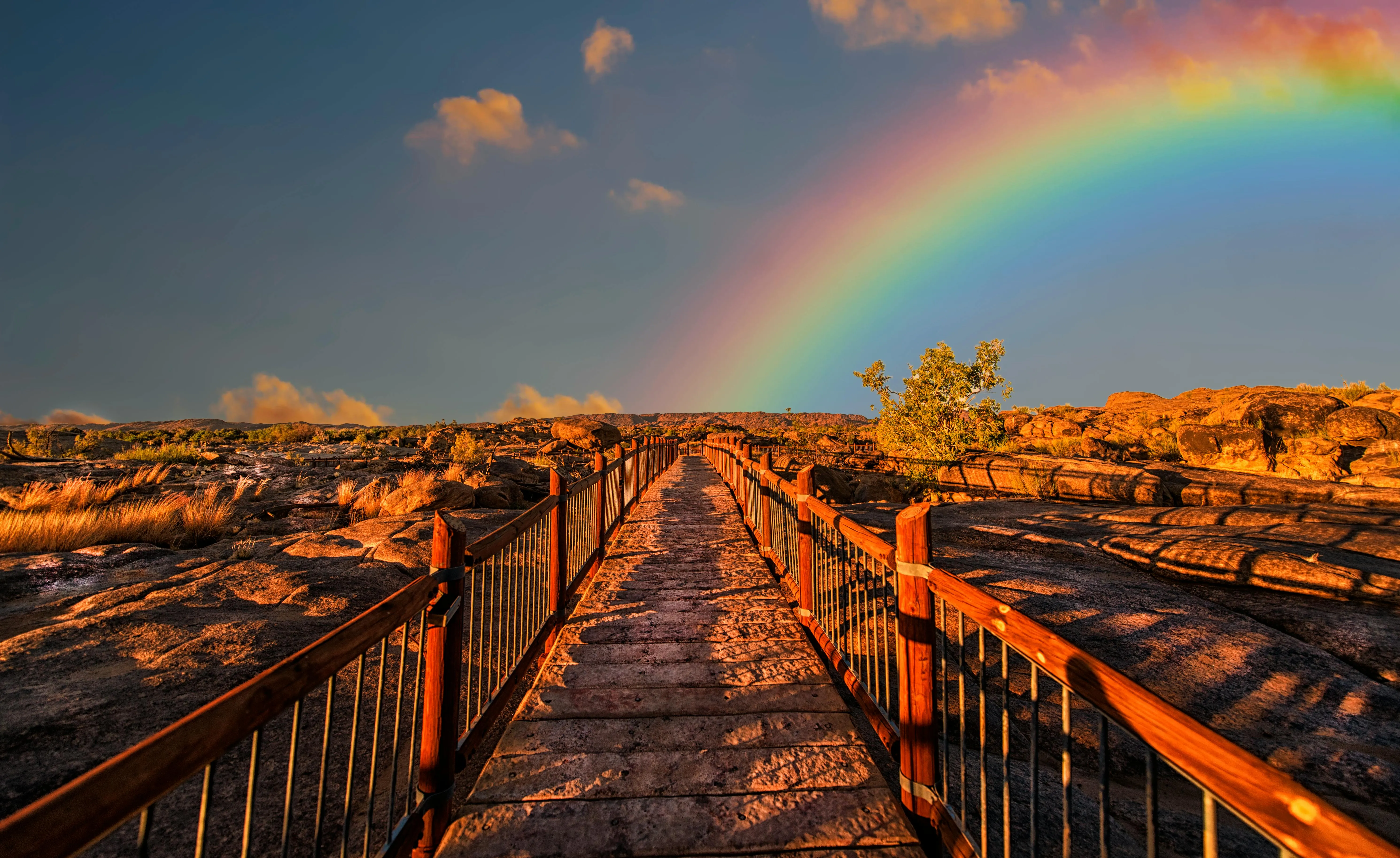 Rainbow Appearing Over a Wooden Pier at Sunset Image