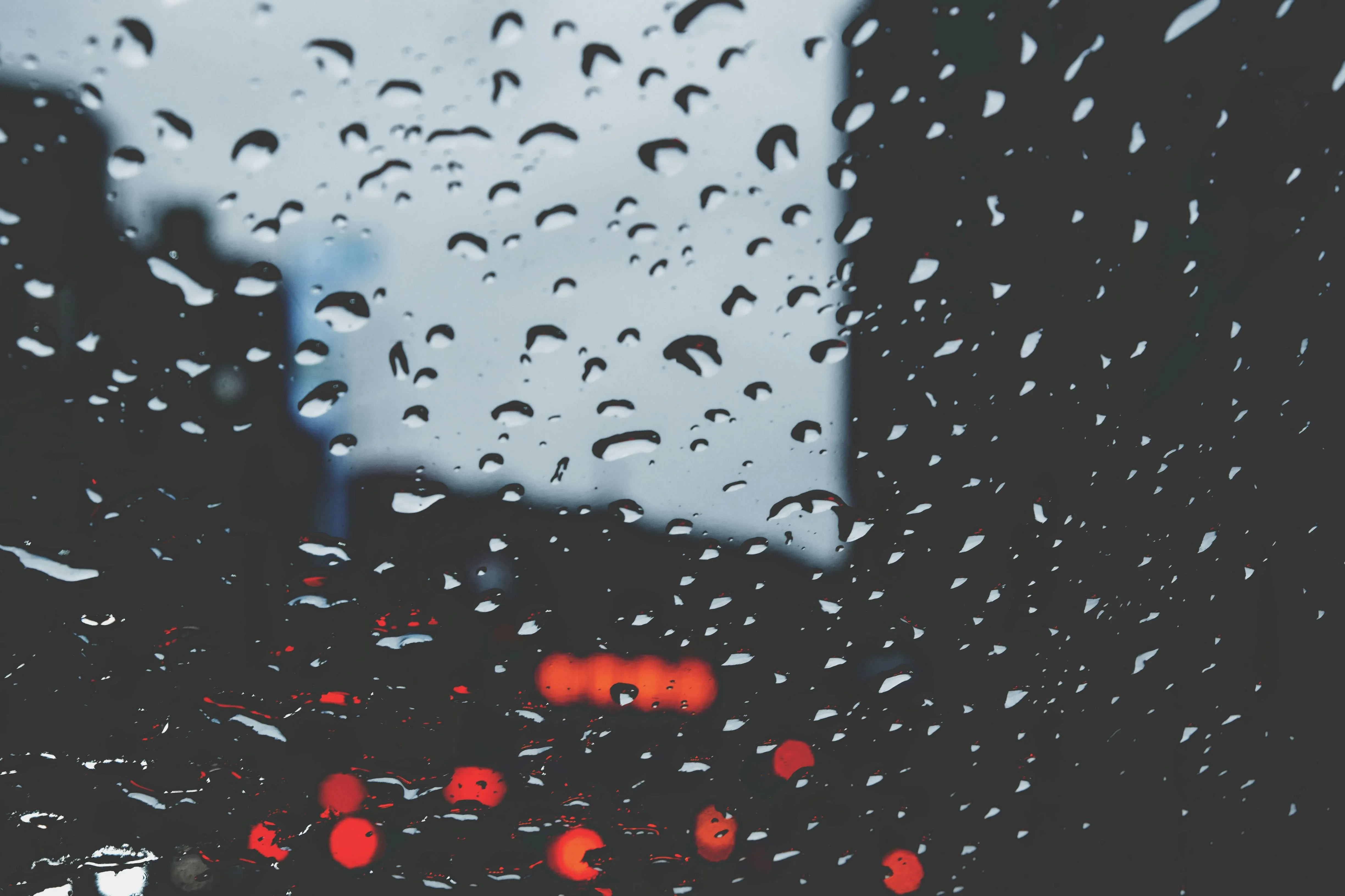 Raindrops on Vehicle Window with Blurred City Traffic Background