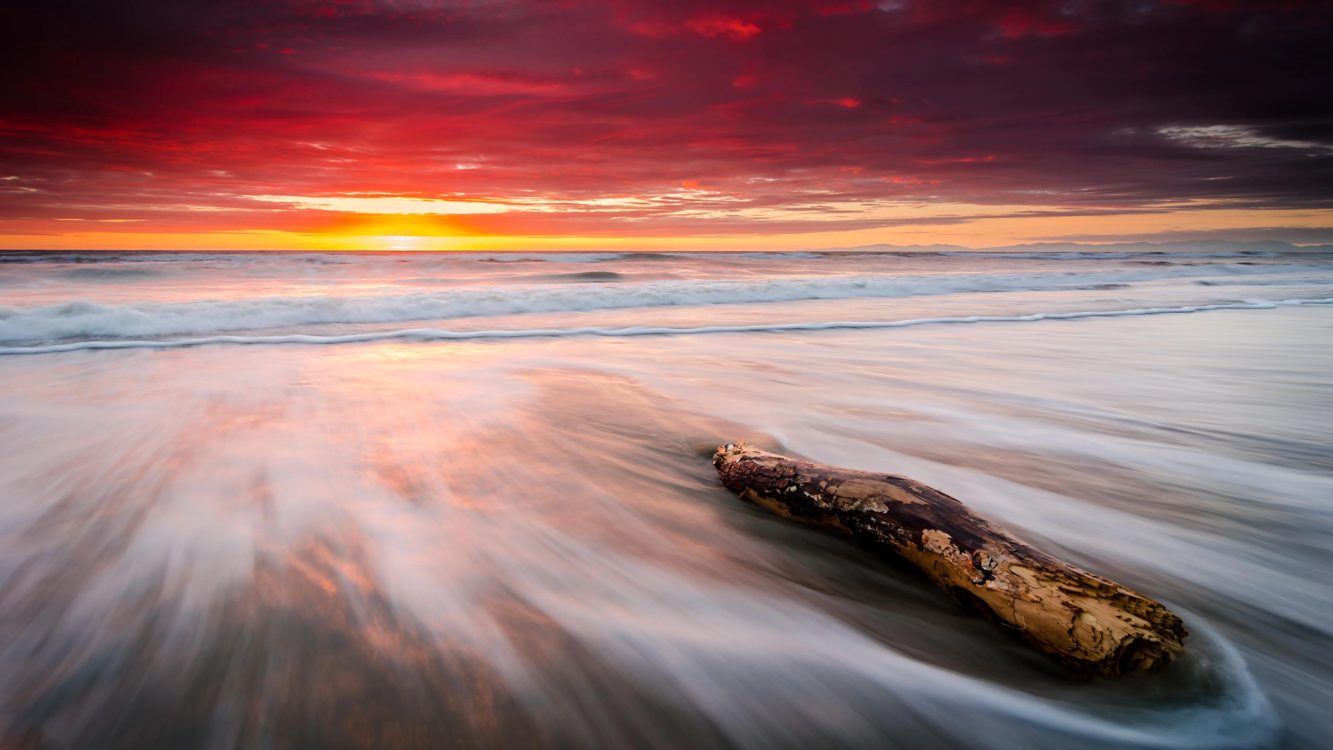 Red and orange sunset lighting waves and beach coast