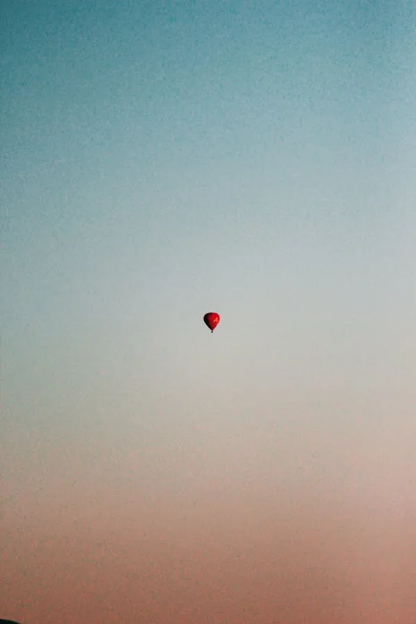 Red Balloon Floating Alone in a Peaceful Sky Wallpaper