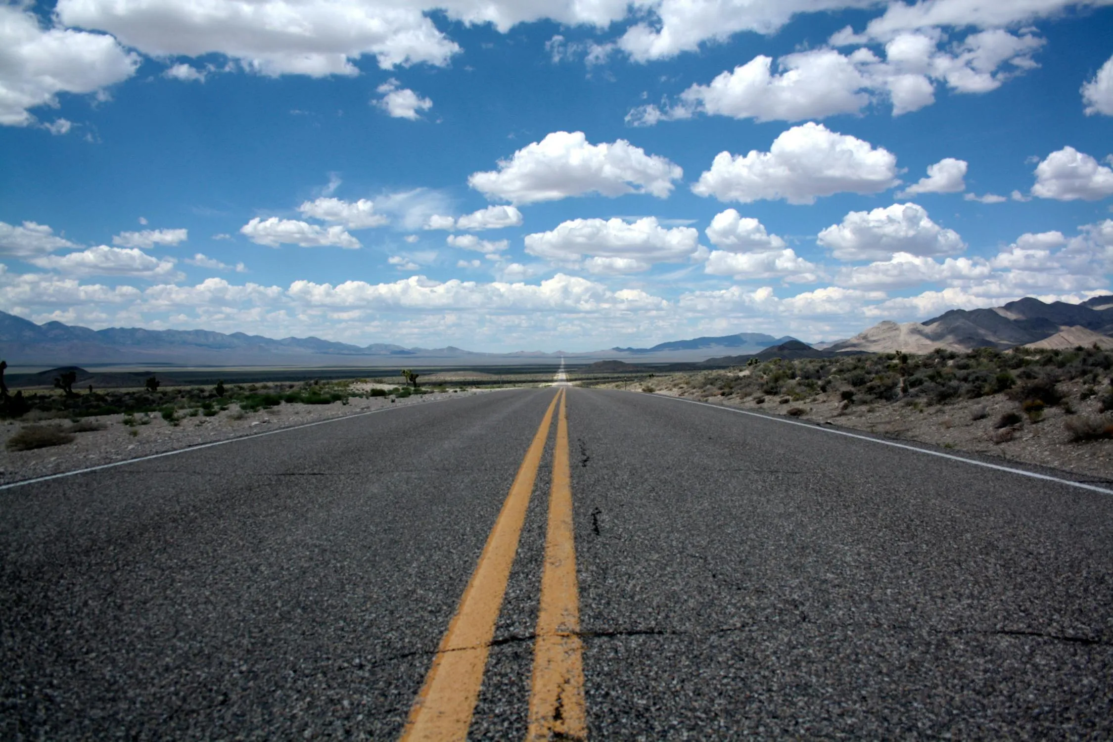 Road Perspective Under Blue Sky with Puffy White Clouds