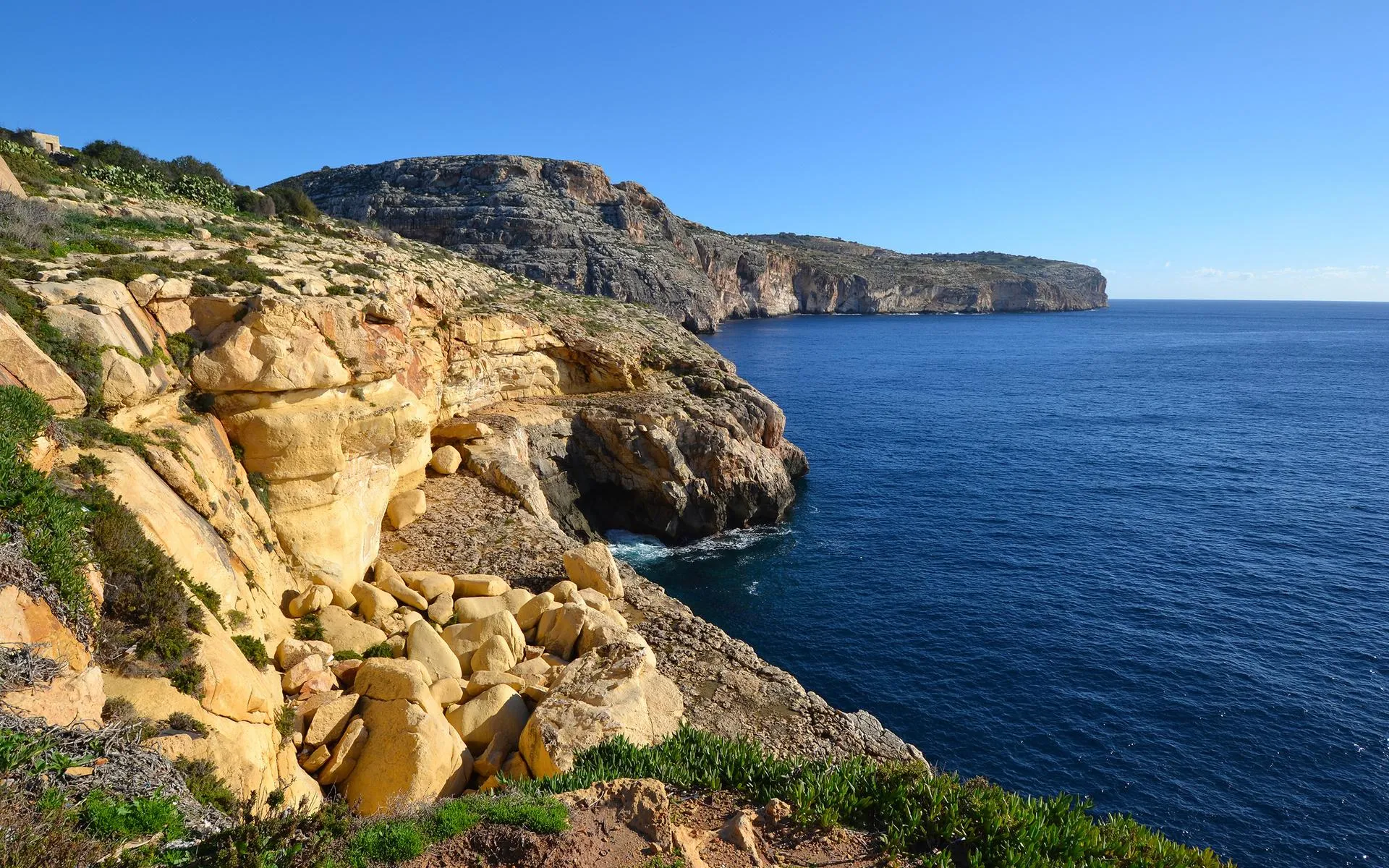 Rocky Cliff Overlooking Calm Ocean Under Clear Blue Sky