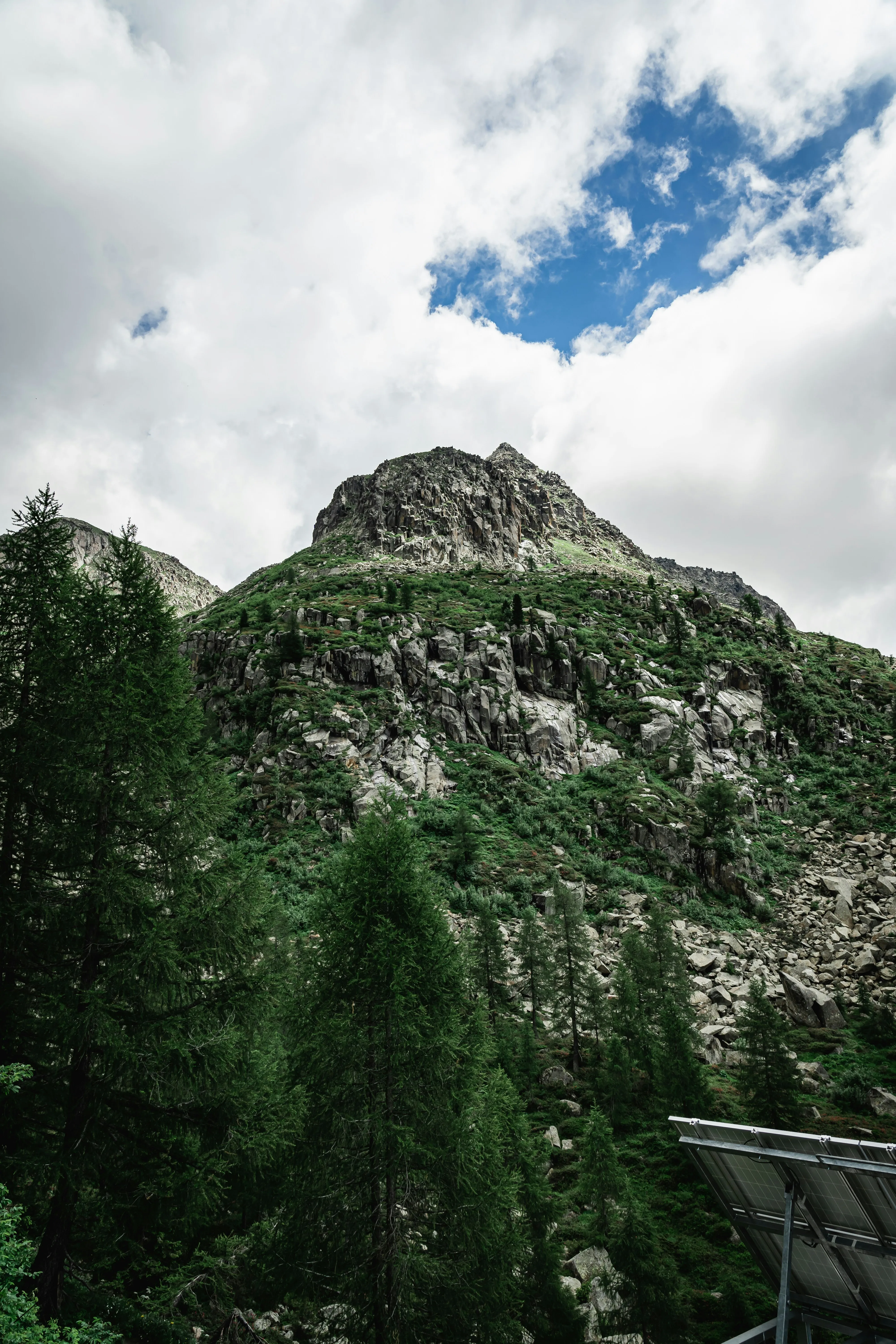 Rocky Green Mountain Peak Under a Cloudy Sky Wallpaper