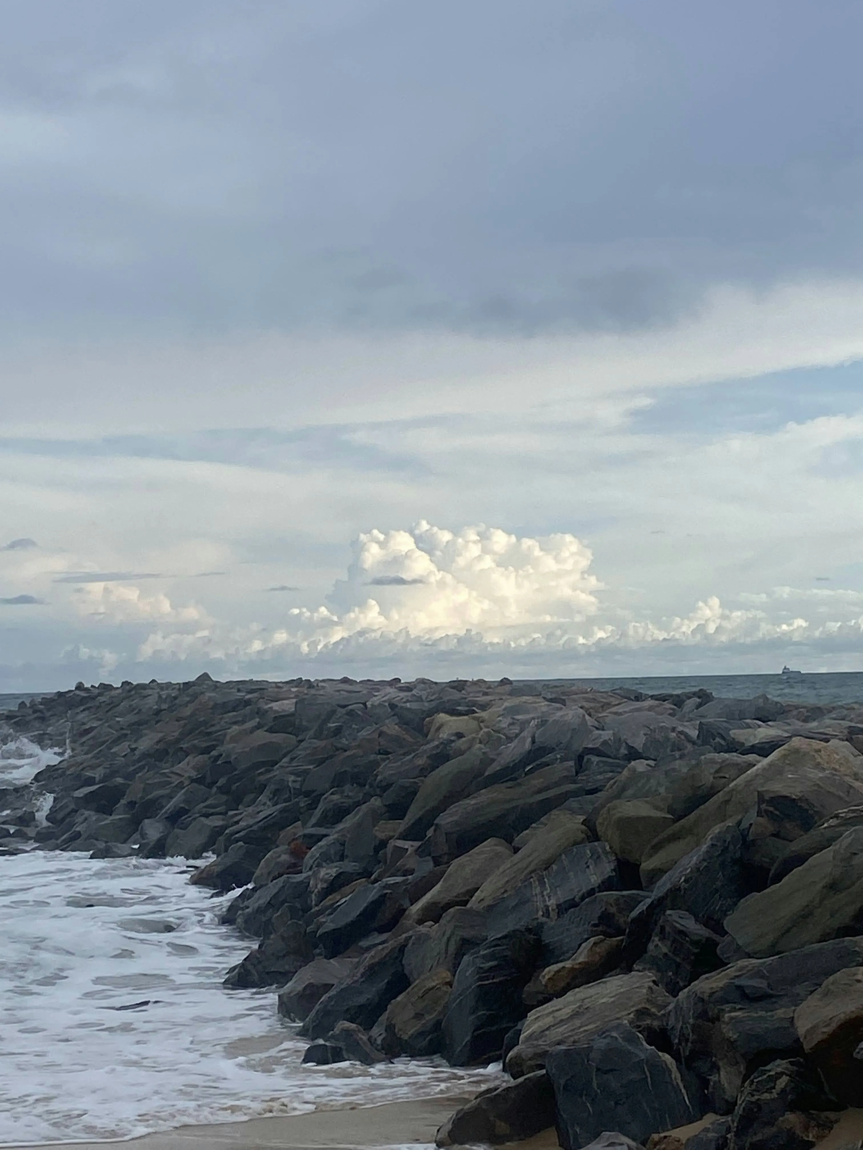 Rocky Shoreline with Waves and Cloudy Sky Background