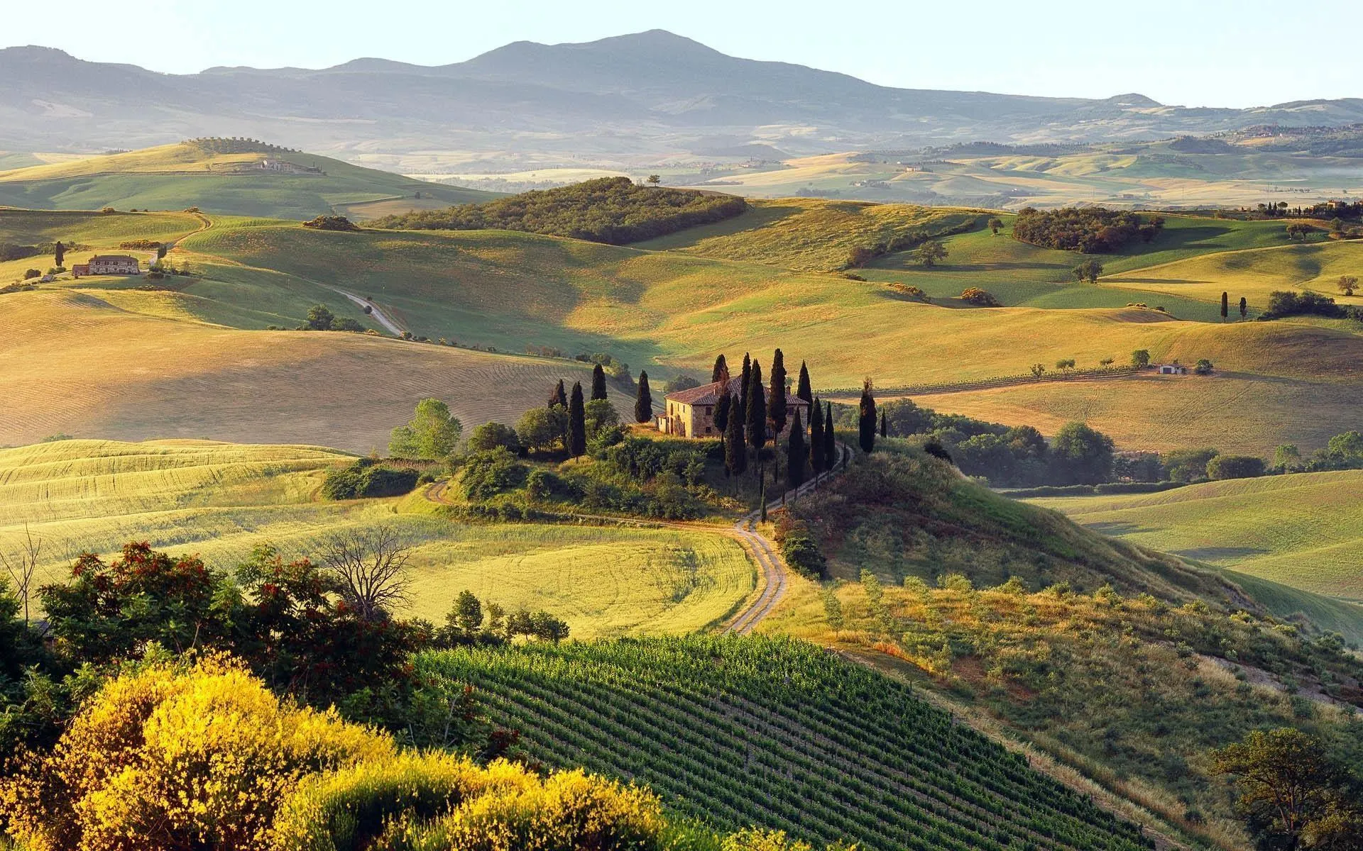 Rolling hills and farmlands under cloudy blue sky