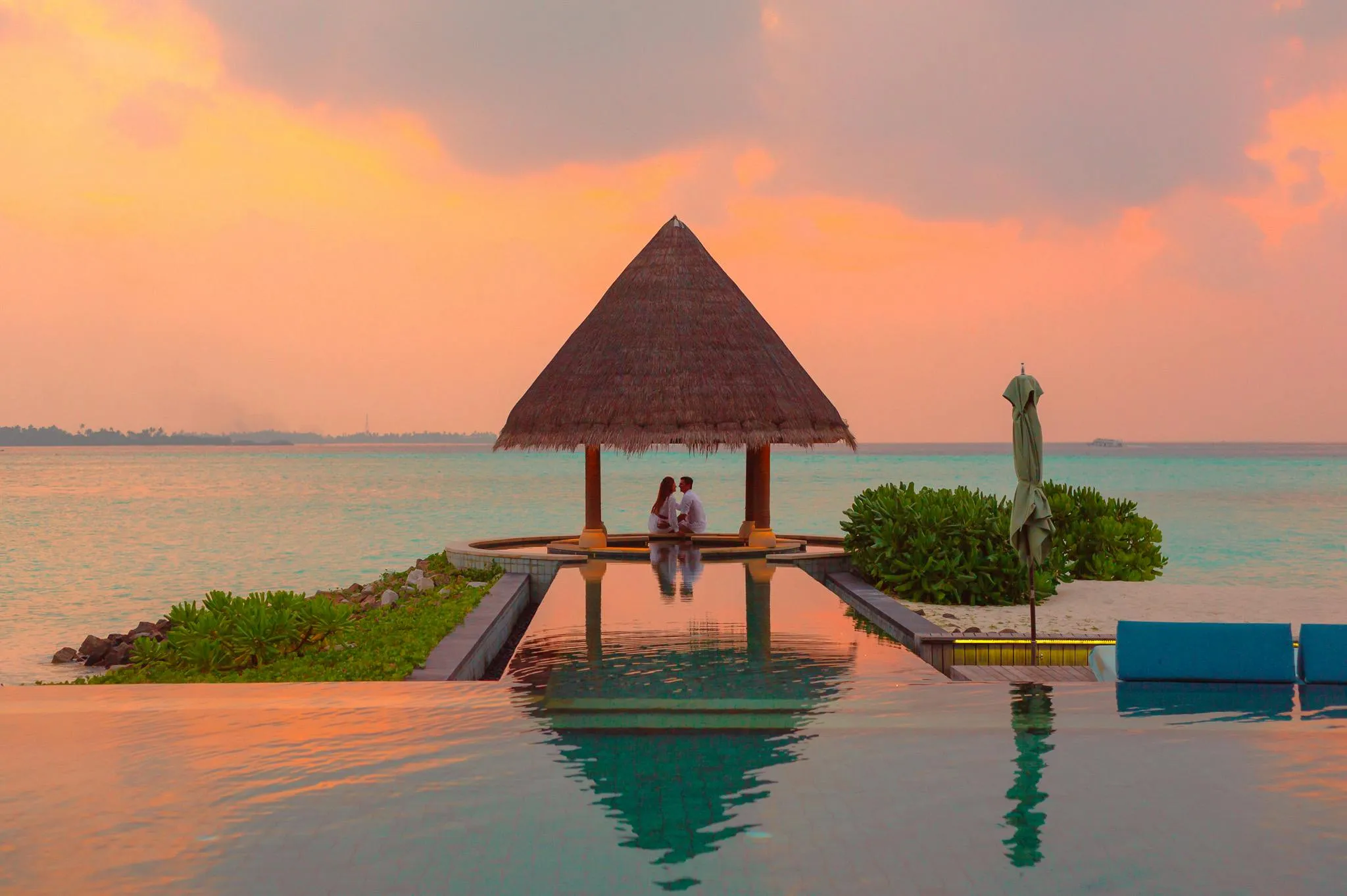 Romantic Couple Sitting Under a Thatched Hut By the Ocean