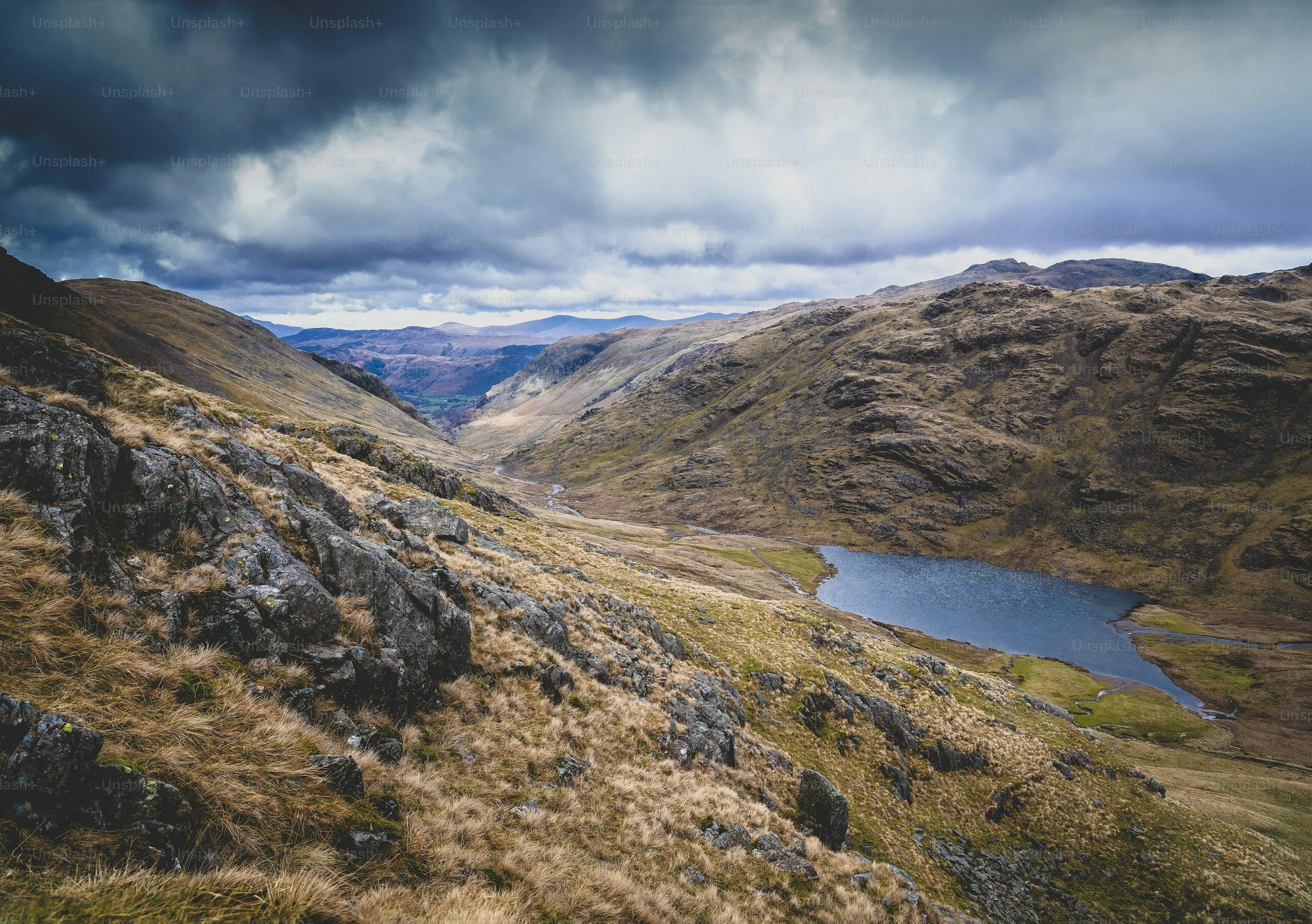 Rugged mountain trail winding above green valley Wallpaper