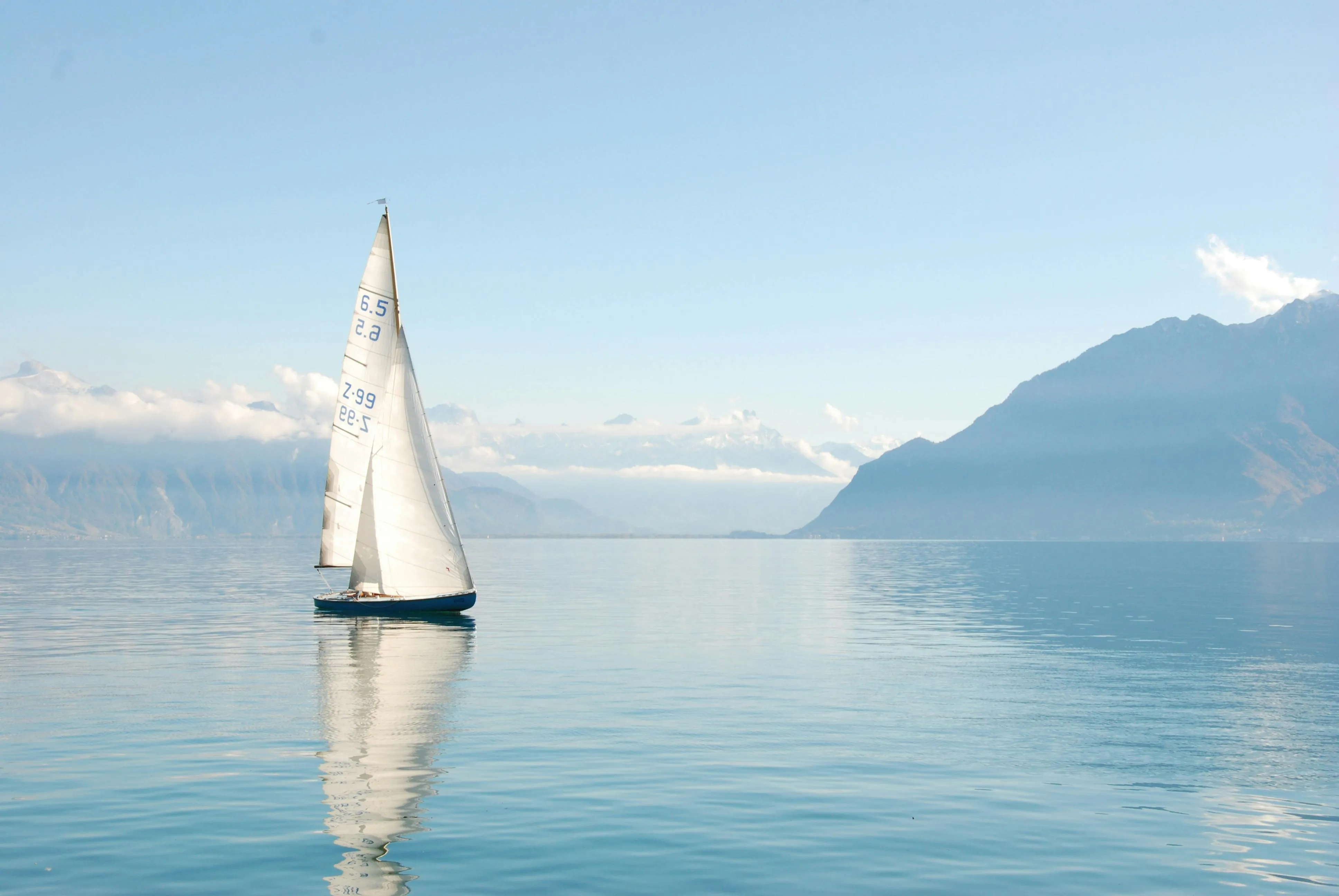 Sailboat Sailing on Clear Water with Mountainous Background