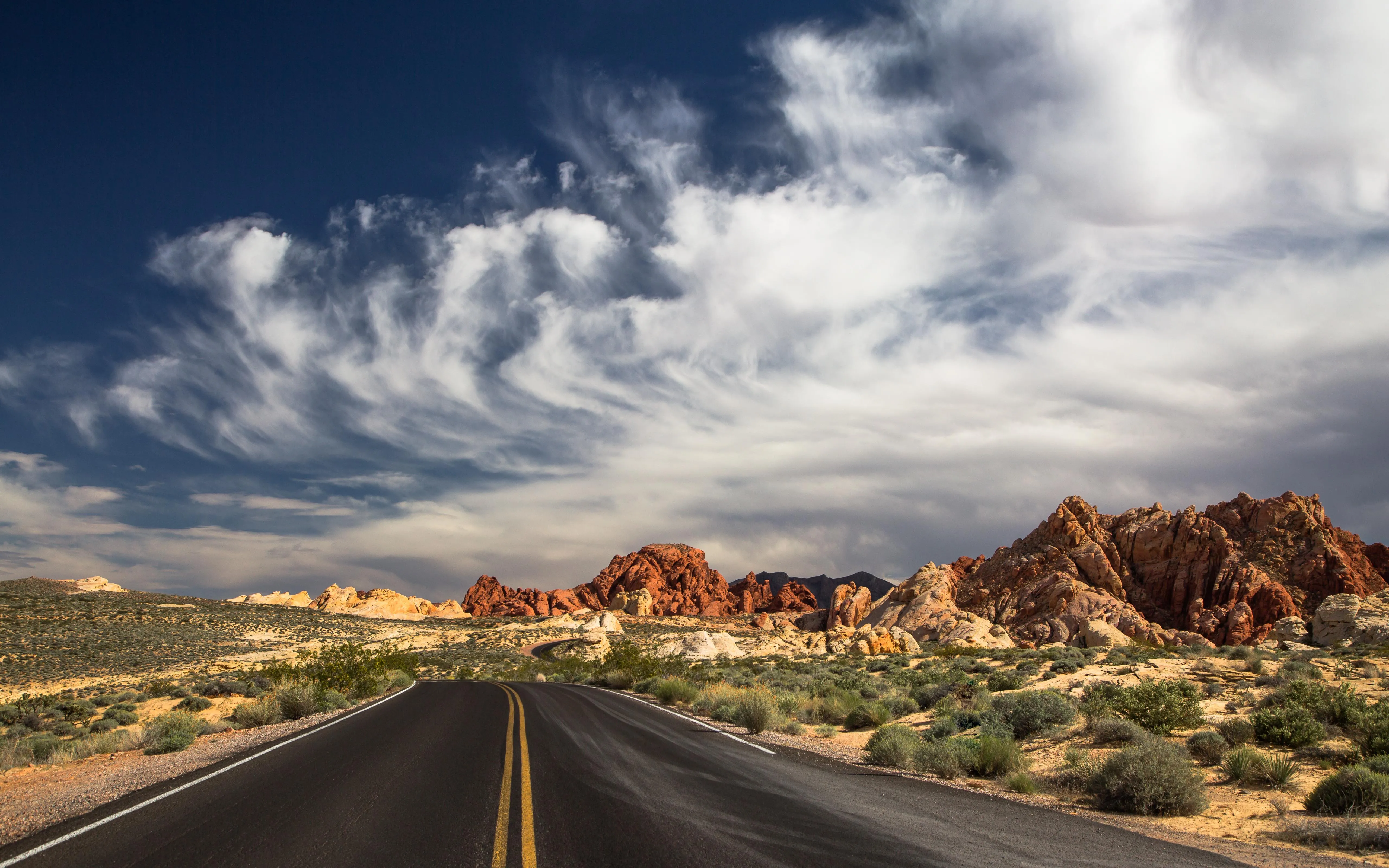 Scenic Desert Road Leading to Colorful Rock Formations
