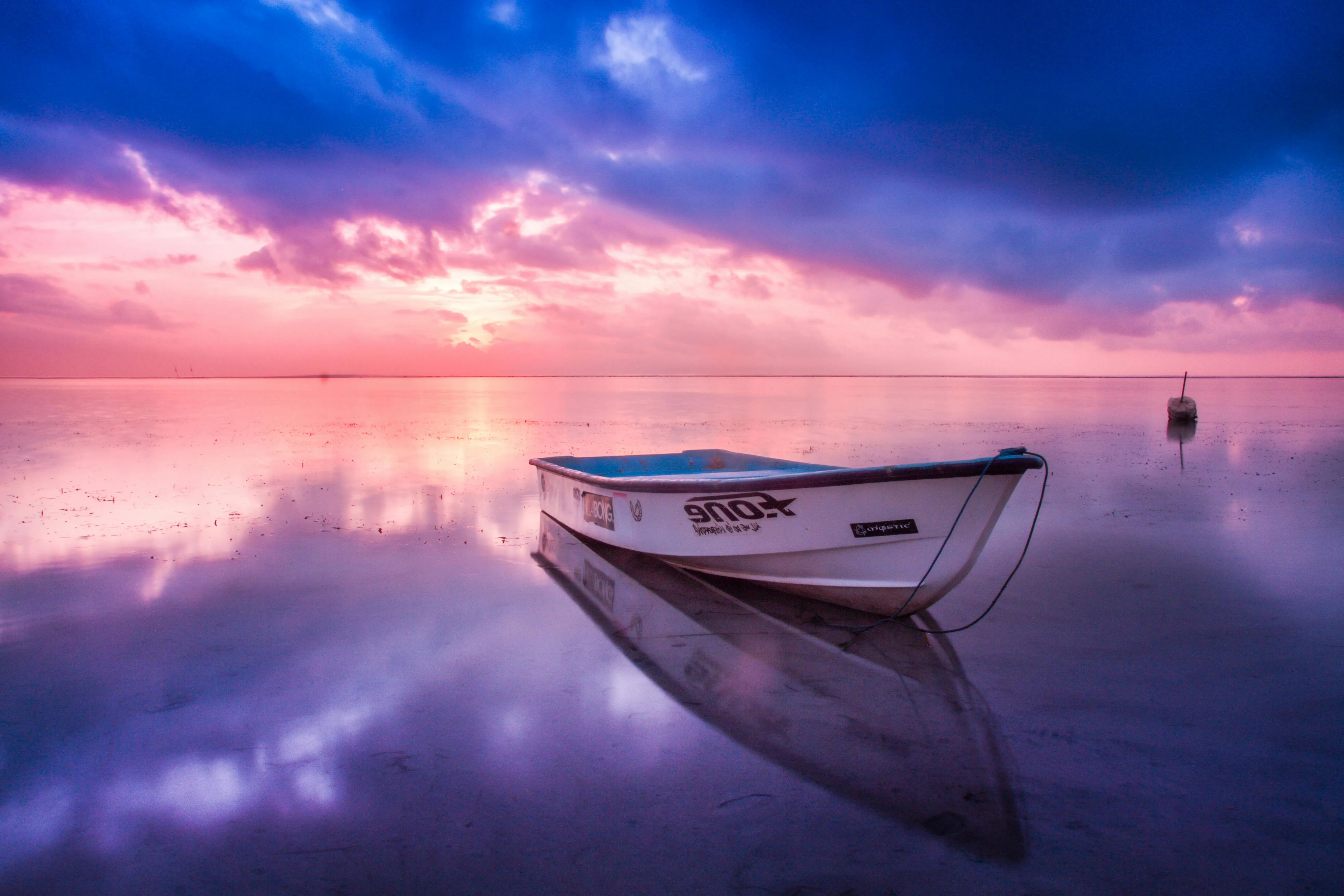 Serene Sunset with Floating Boat and Colorful Sky Wallpaper