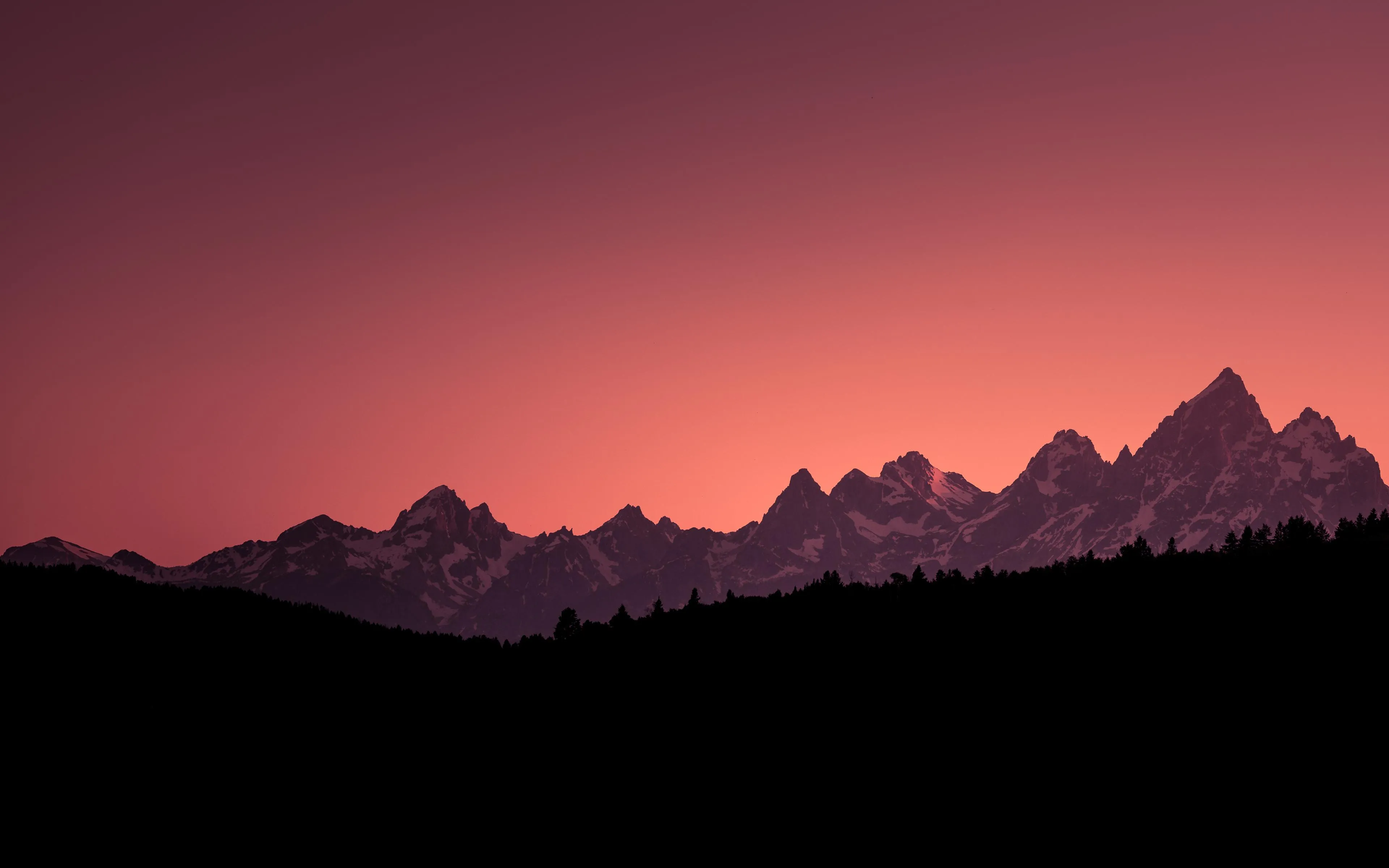 Silhouette of Mountain Peaks Against Red Sunset Sky