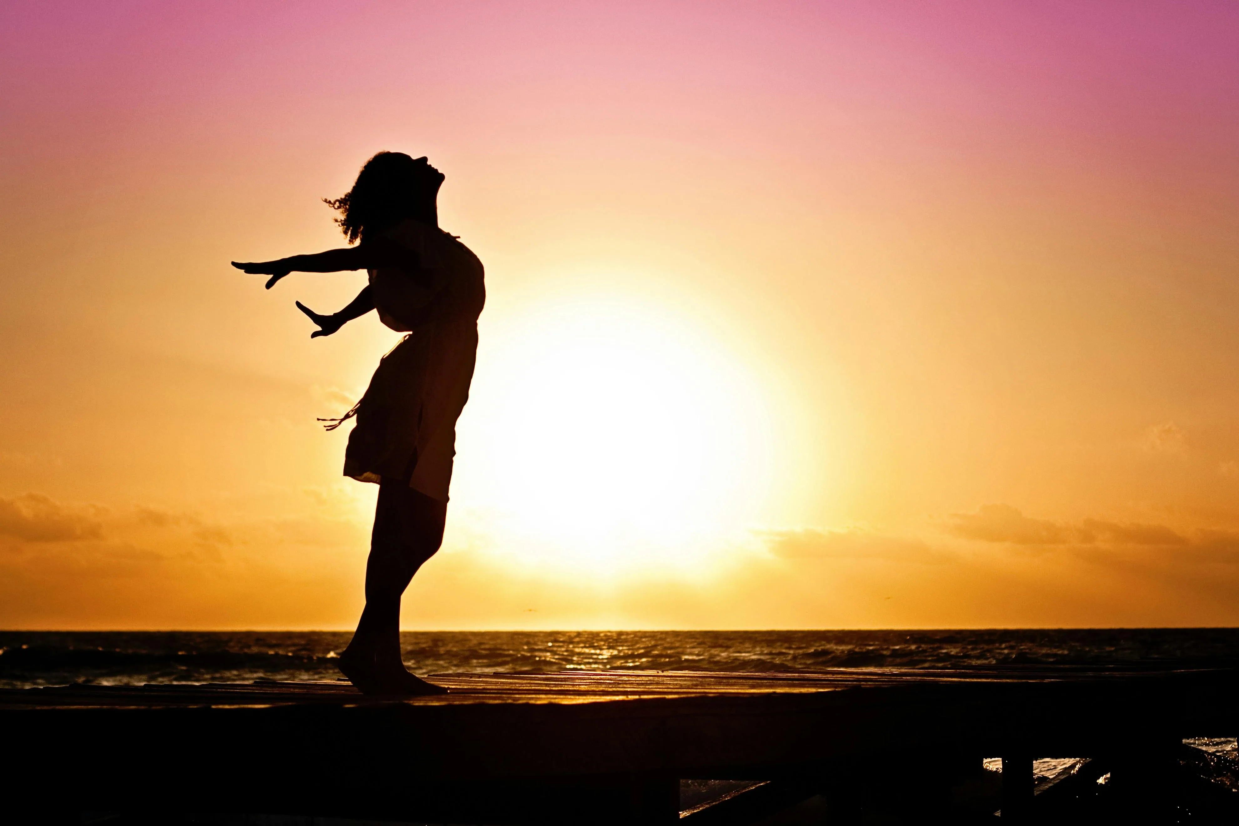 Silhouette of Person Dancing on Beach Against Sunset