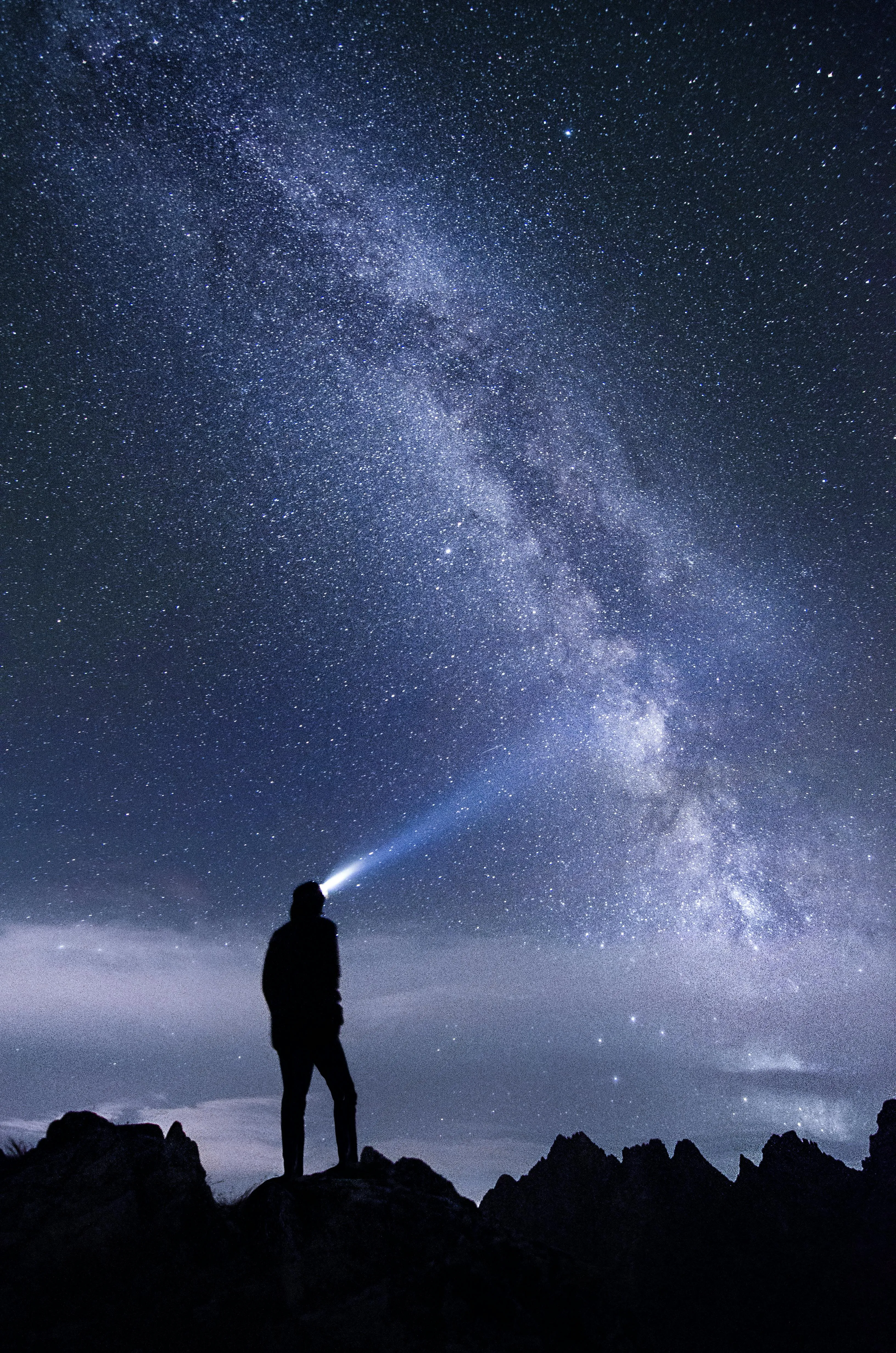 Silhouette of Person Standing Against Starry Night Sky with Clouds
